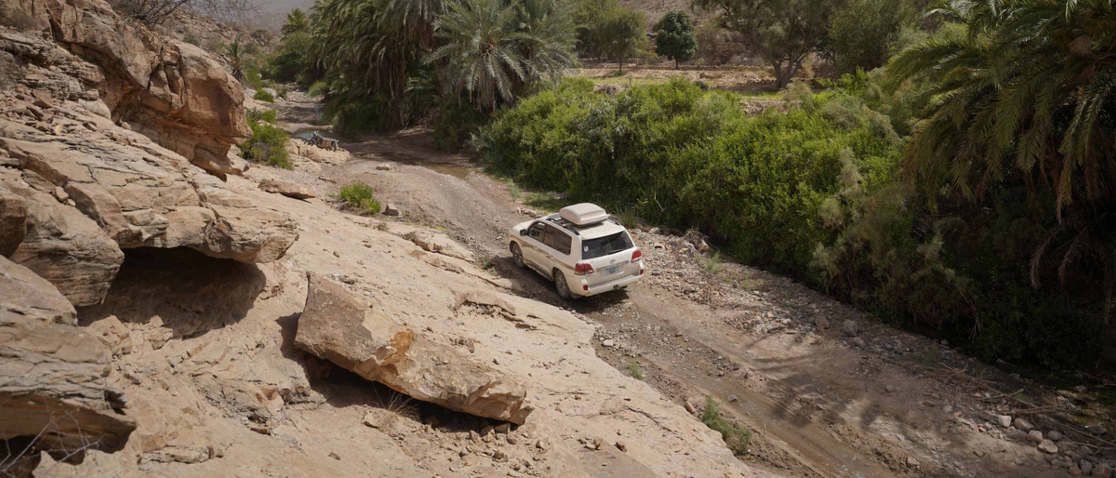 white car driving along a rocky remote road