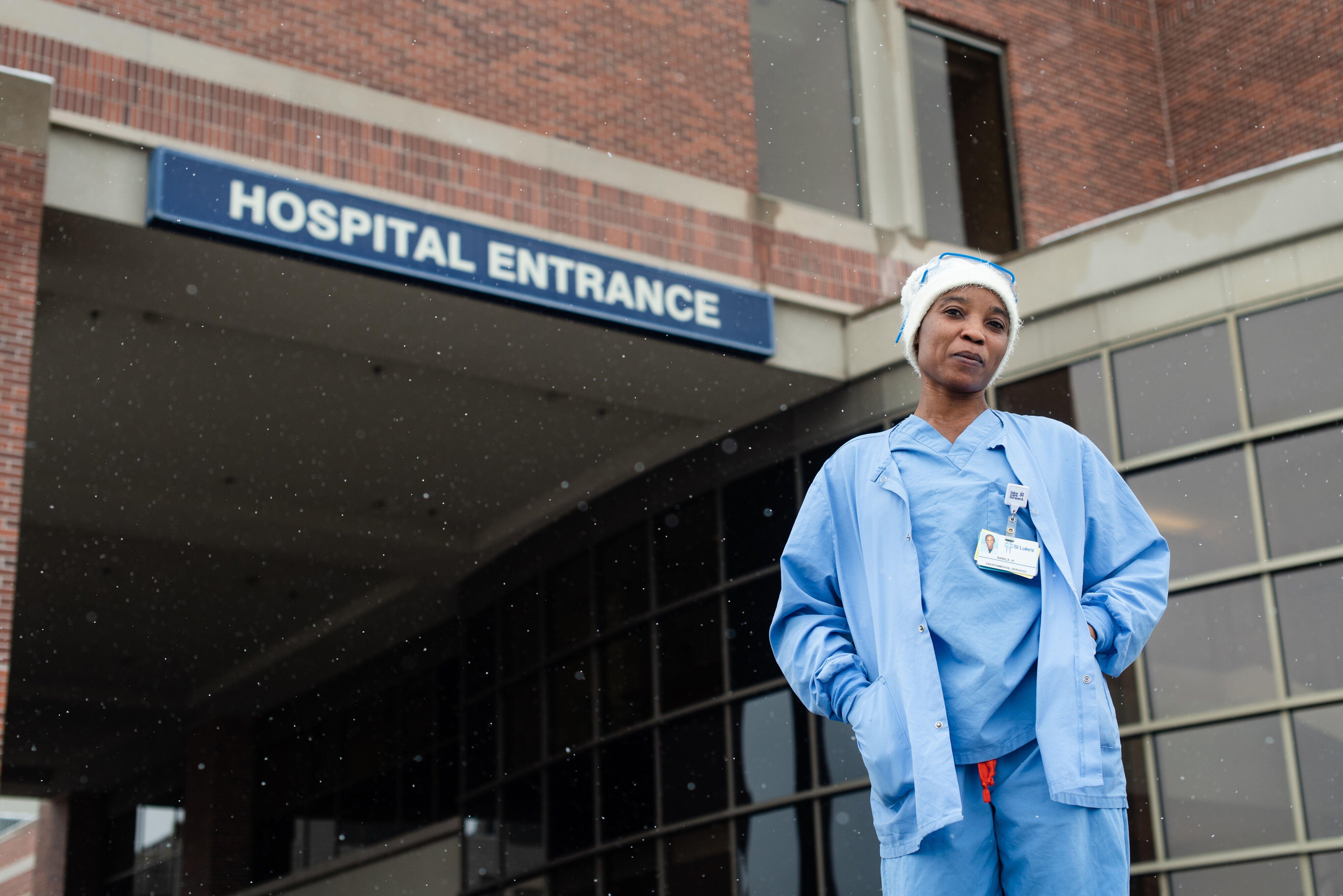 Nabila, an environmental service technician and refugee, in front of the hospital where she works