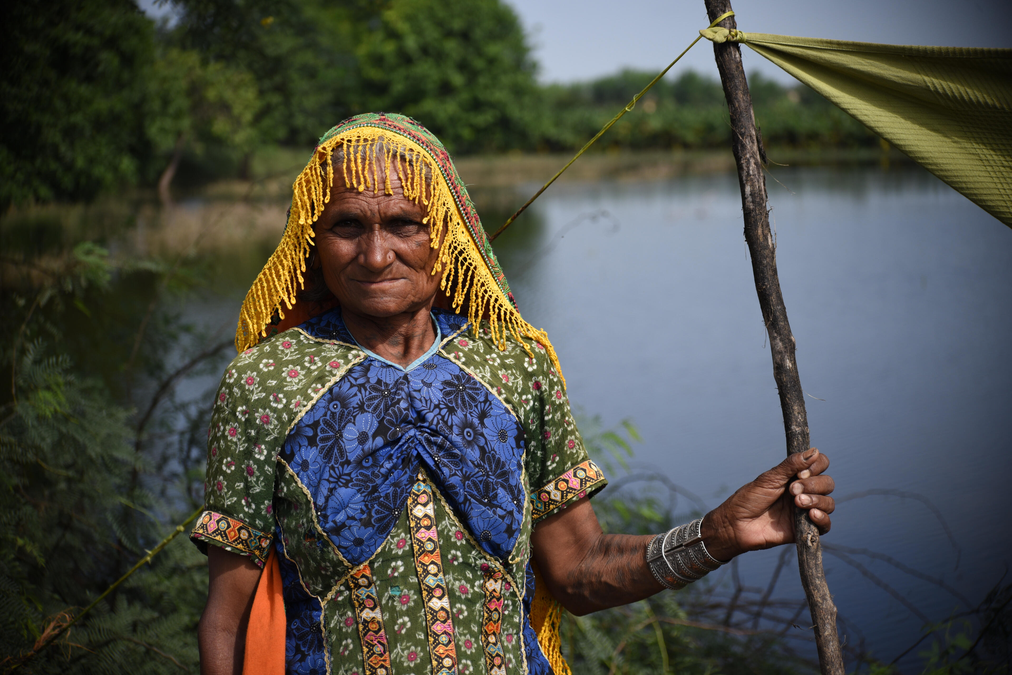 An elderly woman stands by flooded land in Pakistan