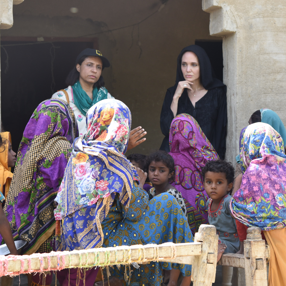 앤젤리나 졸리는 홍수와 파키스탄으로 피해를 본 여성들을 방문합니다. 몇 명의 소녀들이 사진의 정면을 바라보고 있습니다.