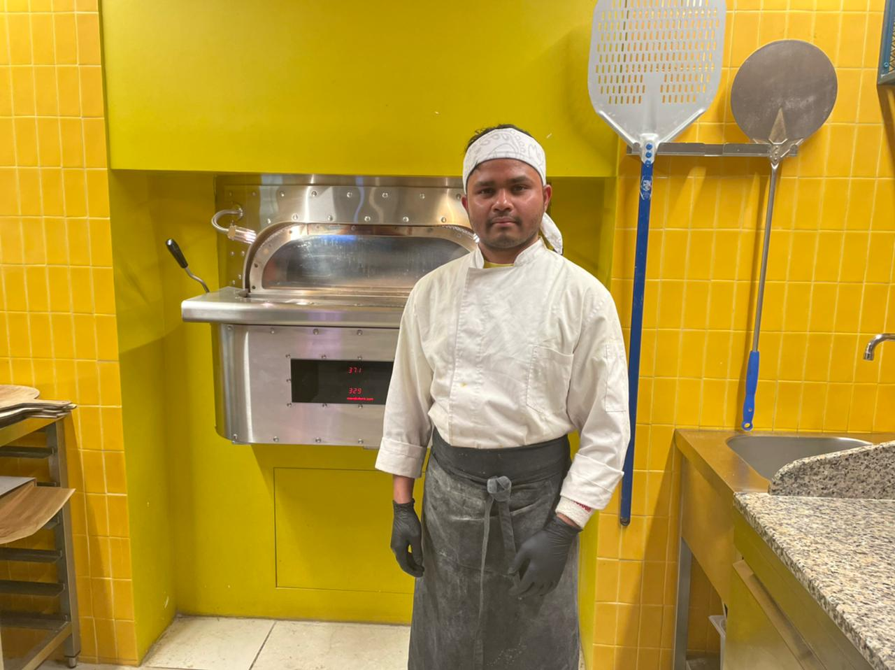 Parwan standing in front of his pizza oven