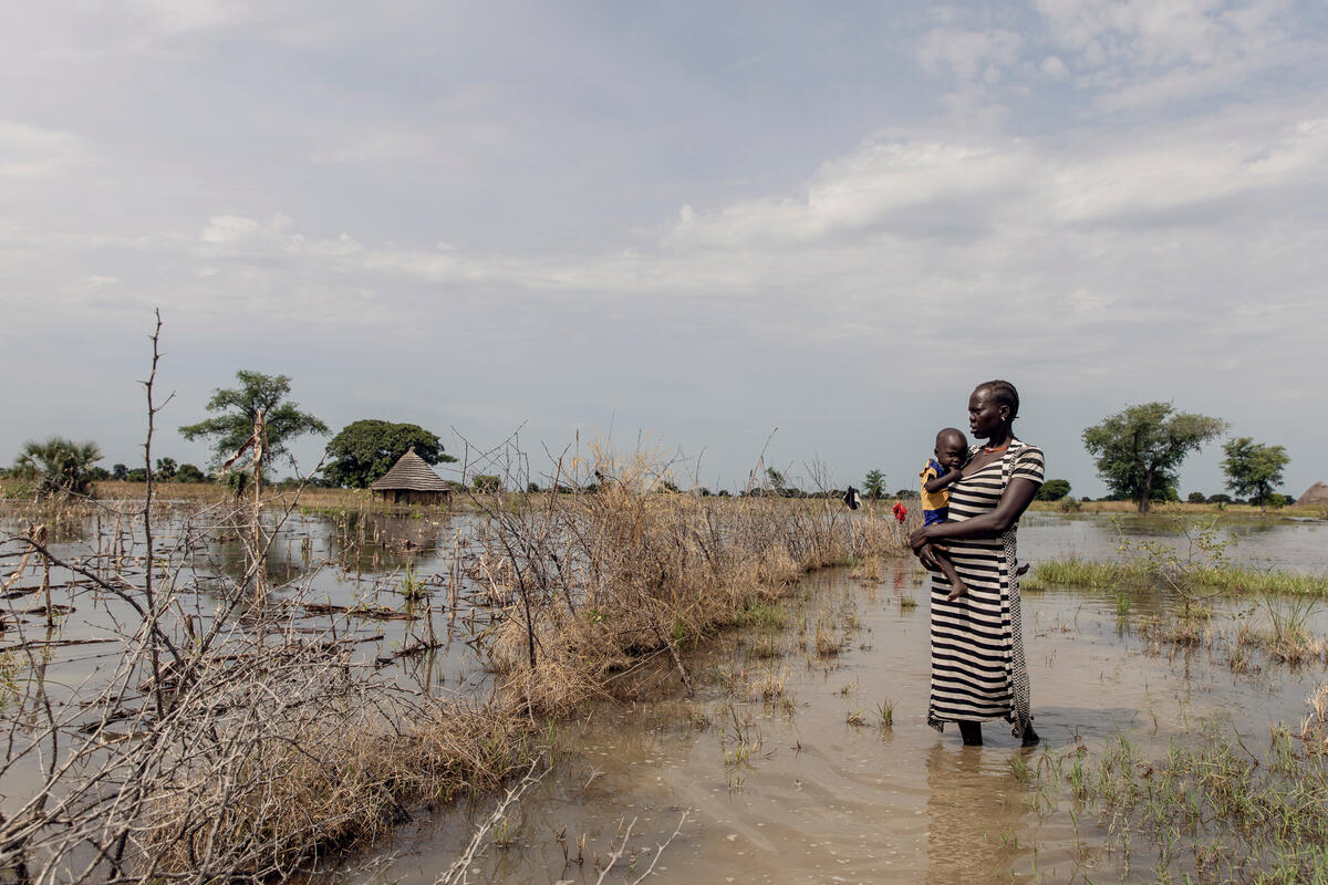 Abuk Deng holding her 4-year-old daughter Nyirou in front of their flooded home in Northern Bahr el Ghazal, South Sudan.