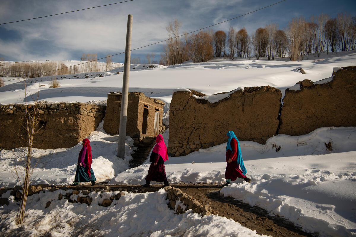 People walking across a snow-coated landscape in Afghanistan