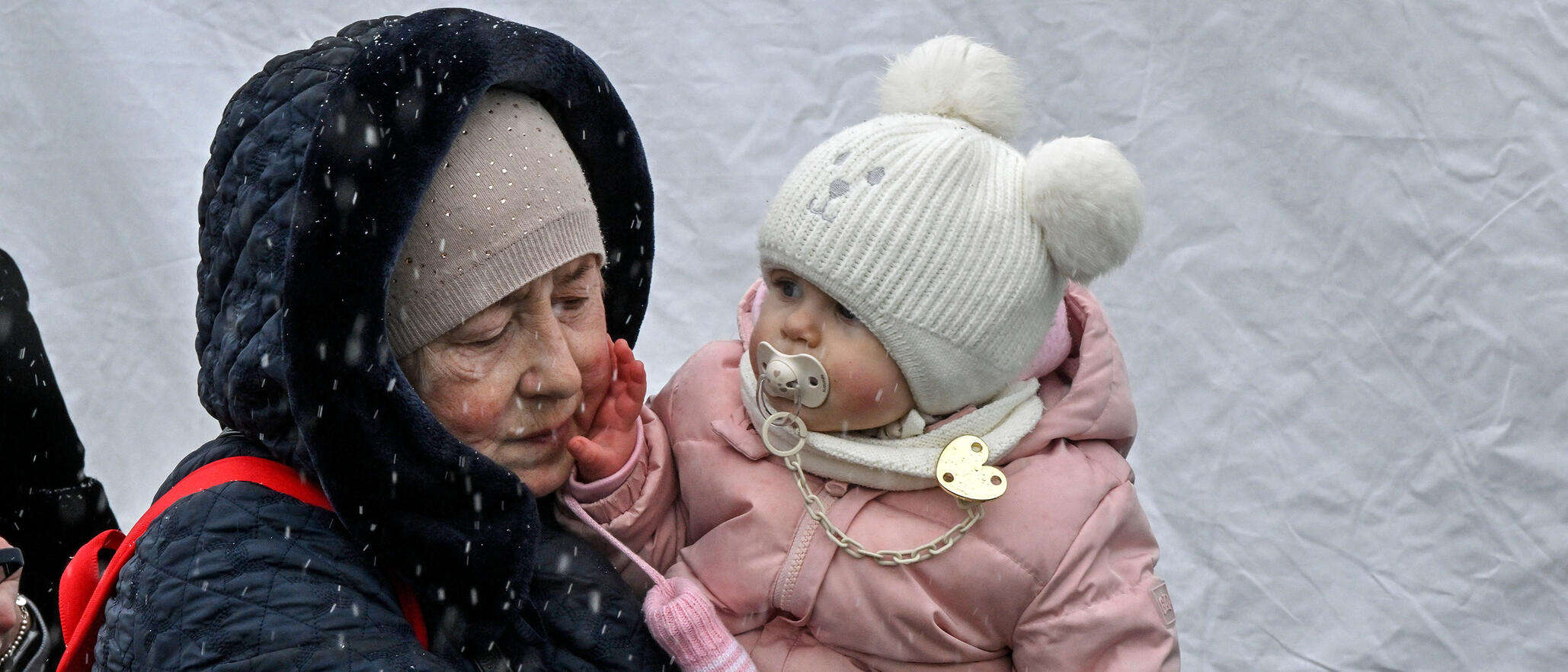 Eine Frau hält ein Baby mit Wollmütze auf dem Arm