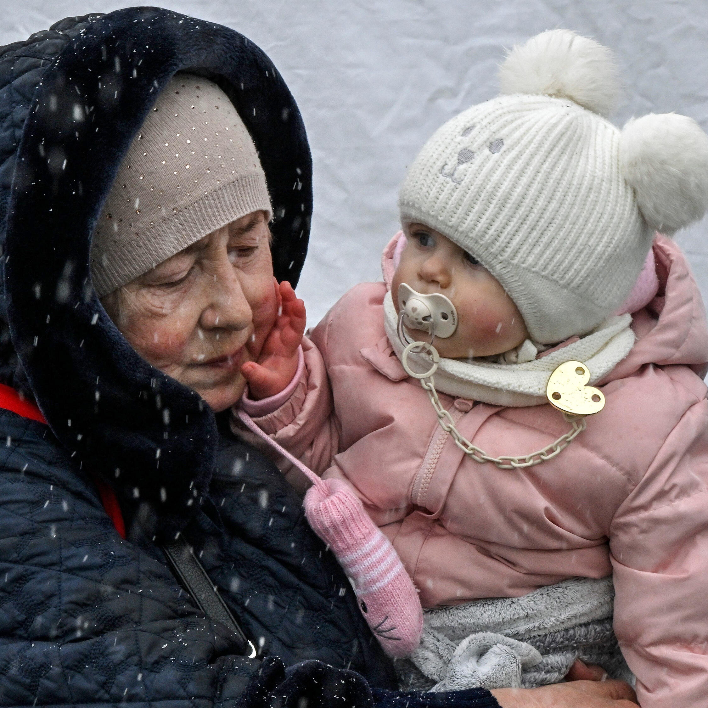 A woman holds her granddaughter during snowfall at the Polish-Ukrainian border crossing in Medyka, Poland.