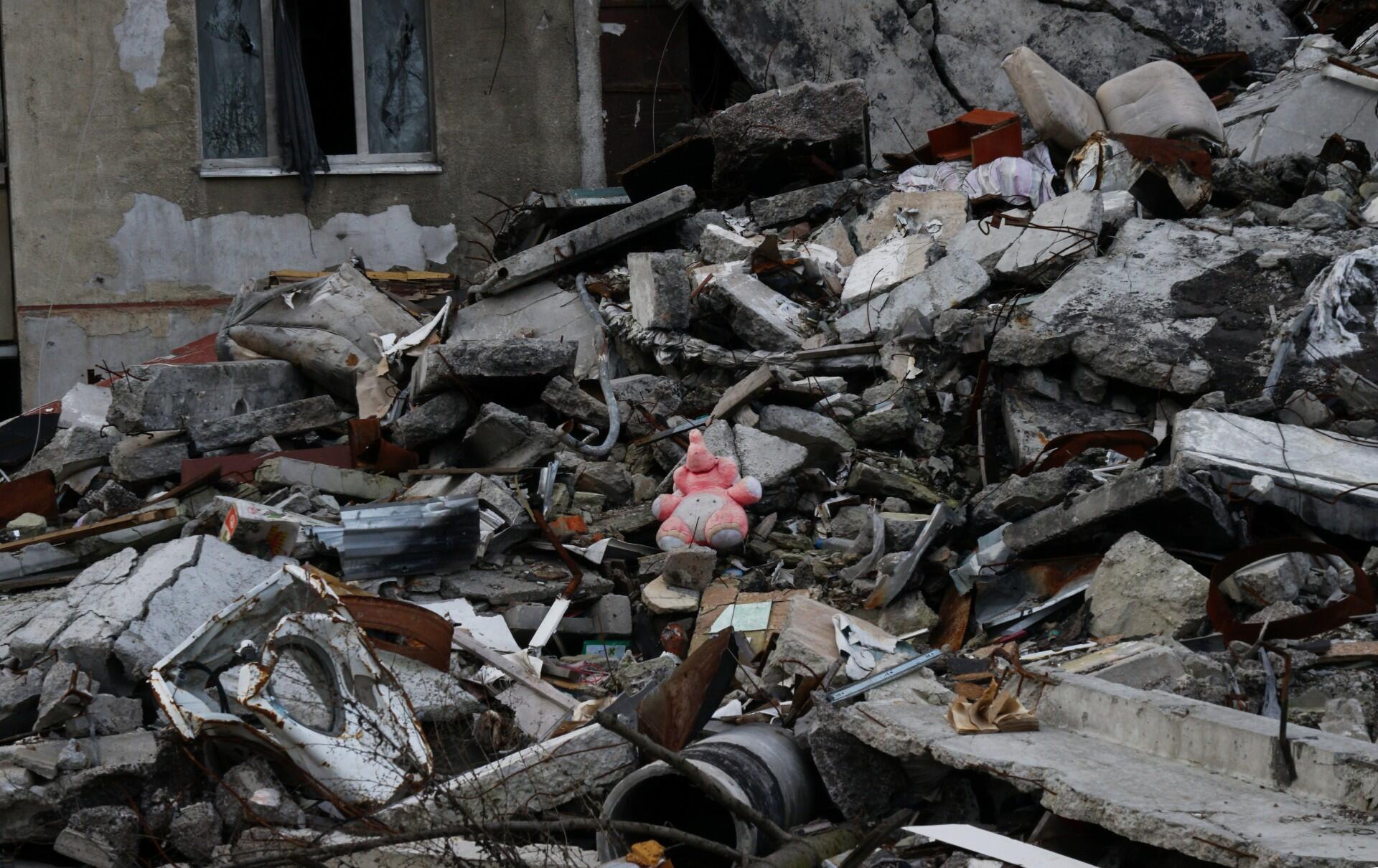 A pink stuffed animal sits amidst a pile of rubble in Ukraine.