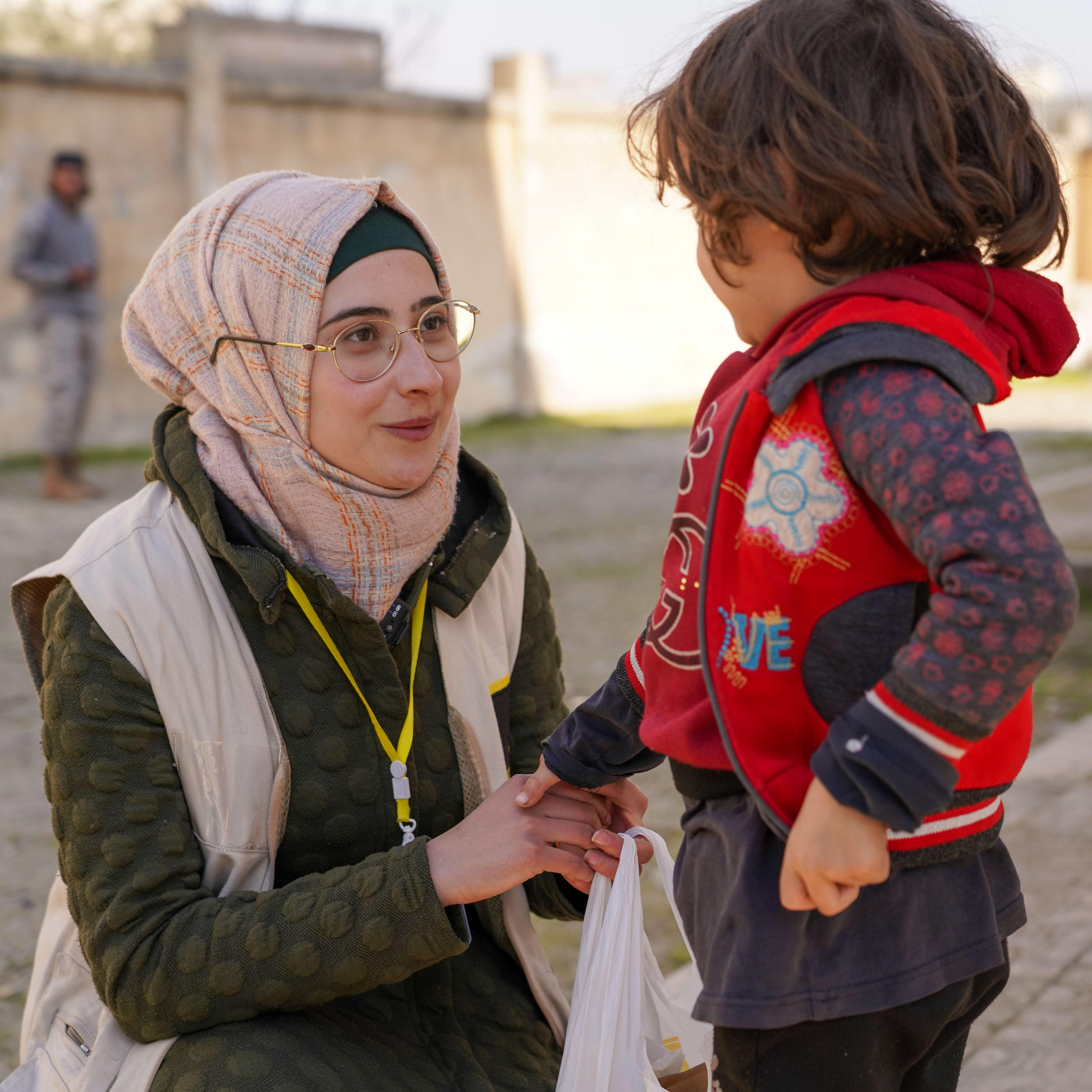 IRC staff member speaks with child. The International Rescue Committee is working rapidly to assist people impacted by the 6 February 2023 earthquake.
