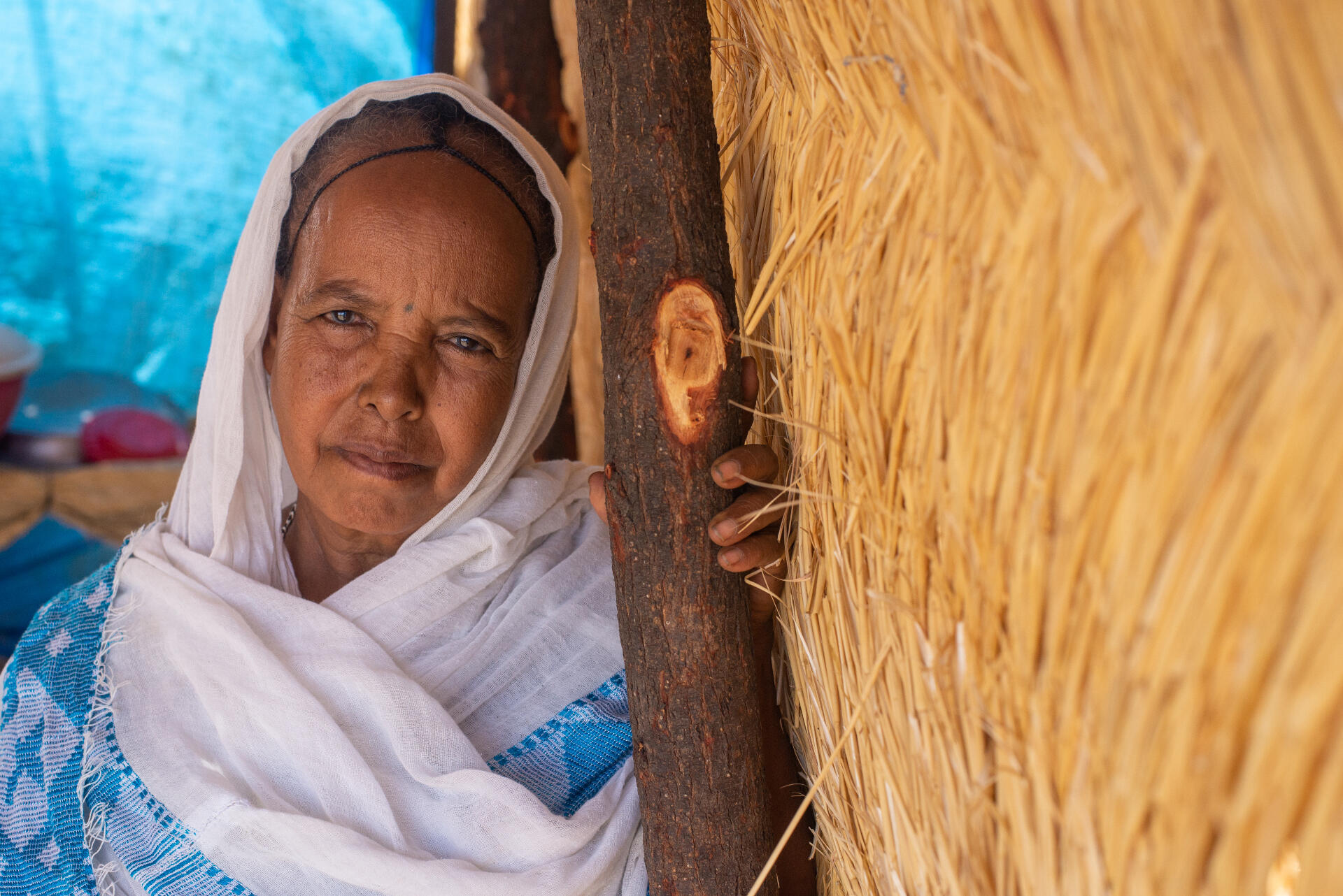 A woman poses for a picture near a makeshift structure in Sudan.