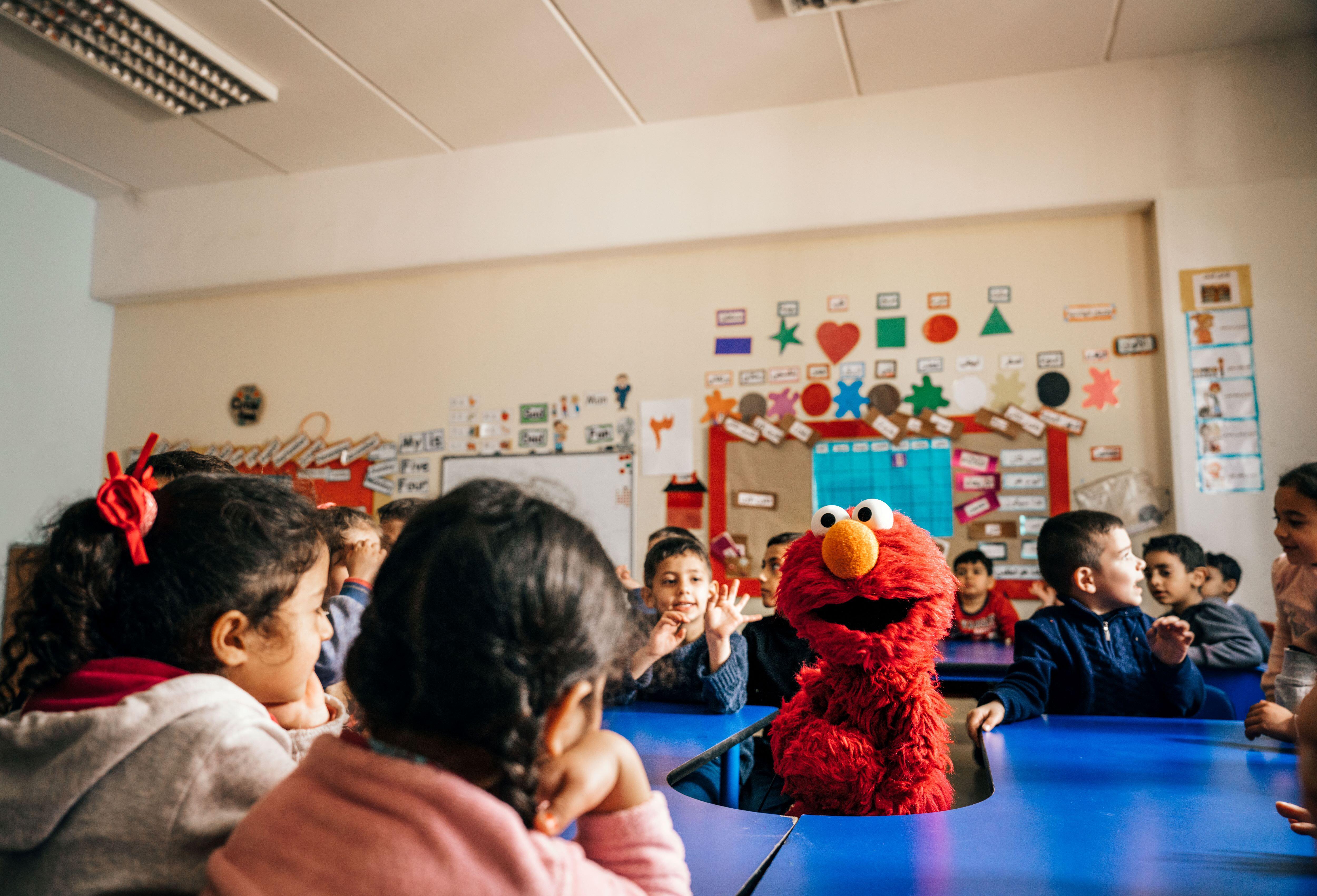 Kinder in einem Klassenzimmer mit einer Figur aus der Sesamstraße