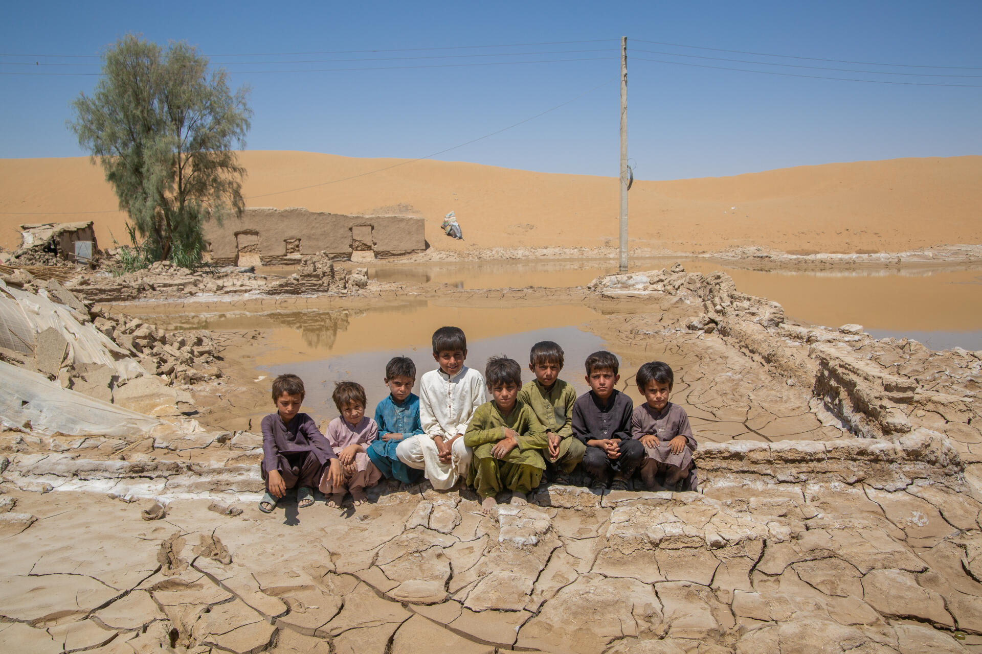A group of kids pose for a picture on a dry and barren landscape.
