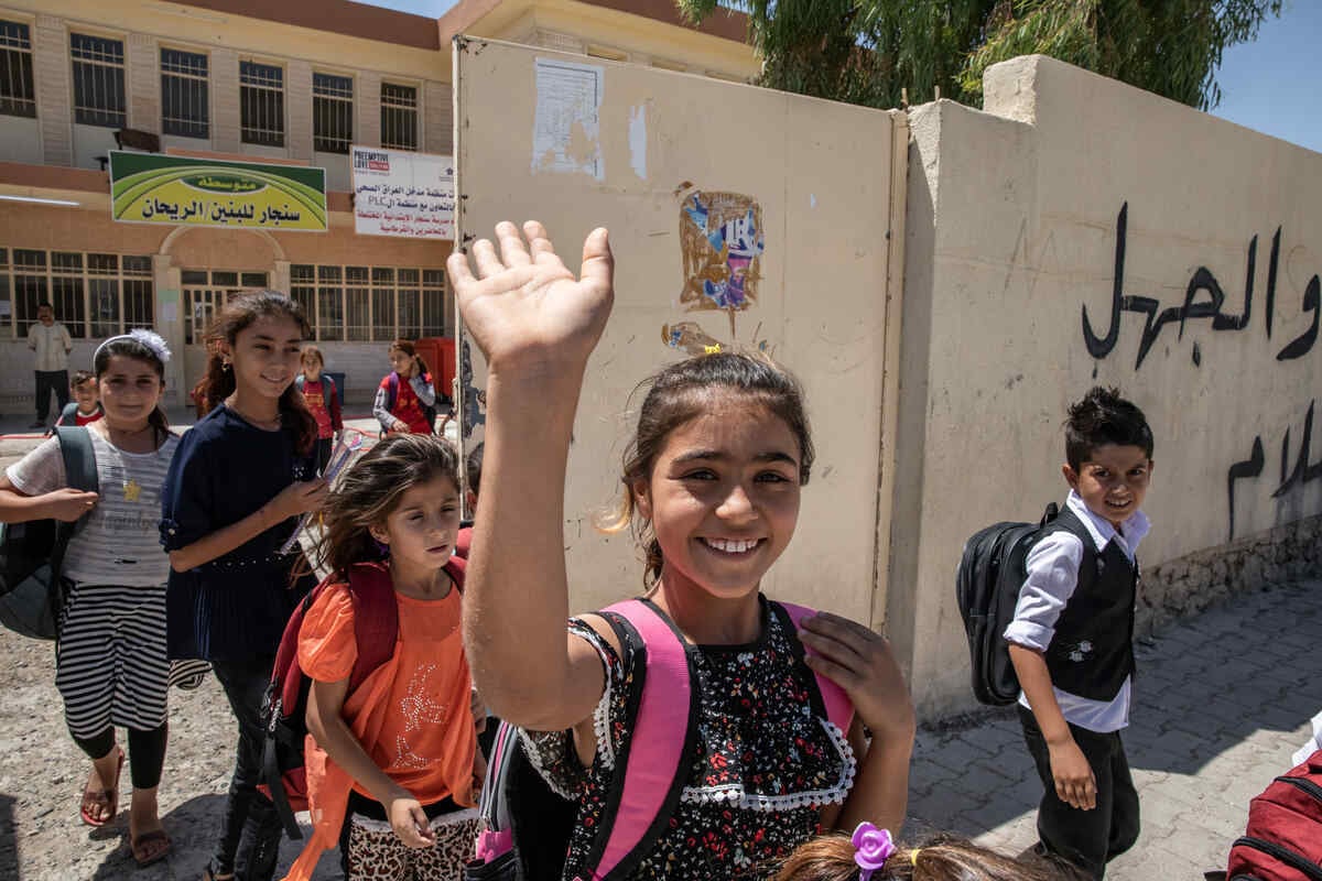 Darin, en ung flicka från Sinjar, Iraq, vinkar utanför sin skola.