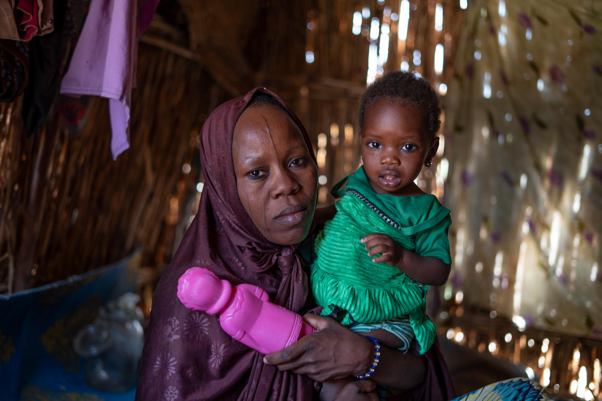 A woman holds her child in her home in Awaridi village, Niger