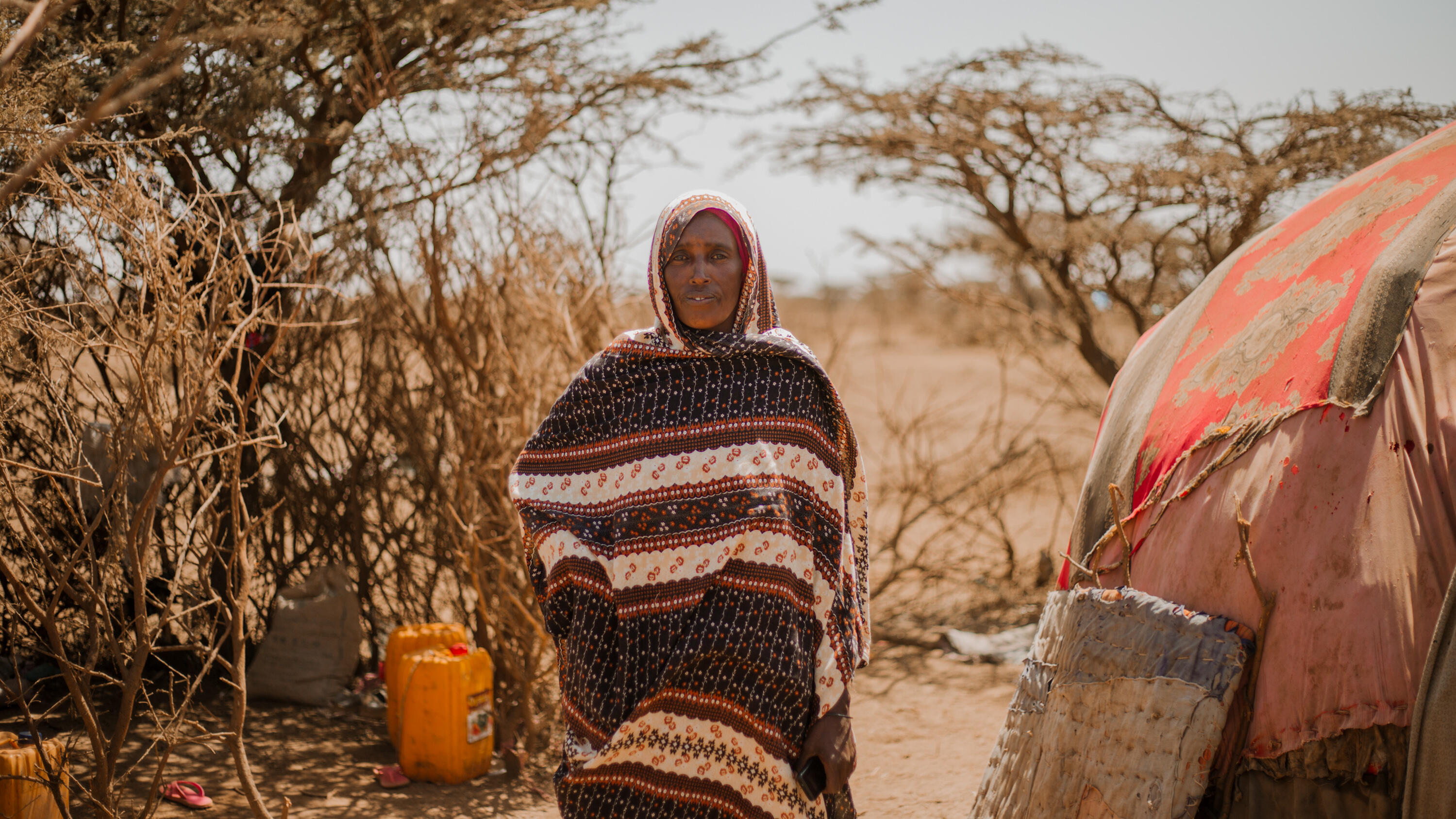 A woman poses for a photo amidst a barren landscape in Ethiopia.