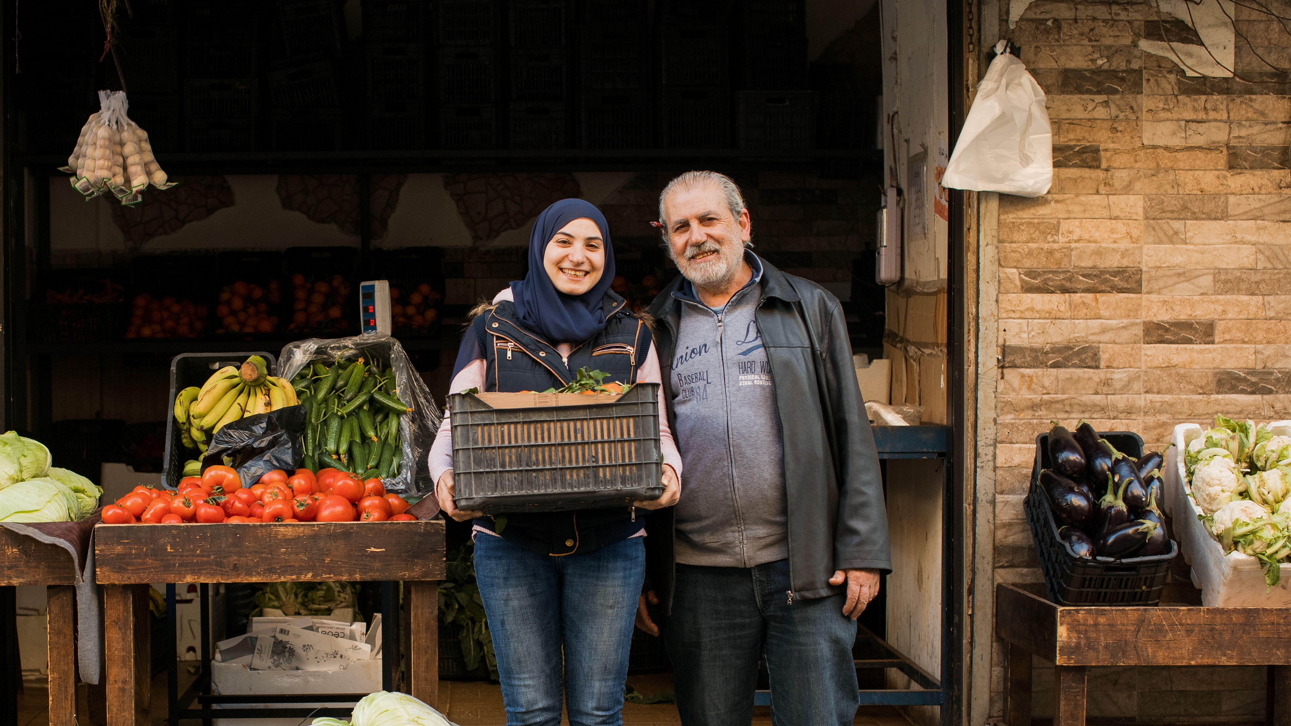 A woman and her father stand outside of their vegetable shop in Lebanon.