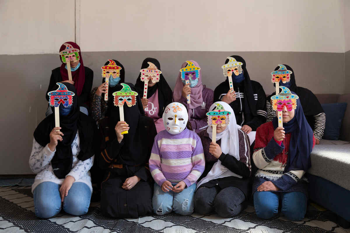 A group of young Syrian refugee girls wearing masks they made during a drawing activity.