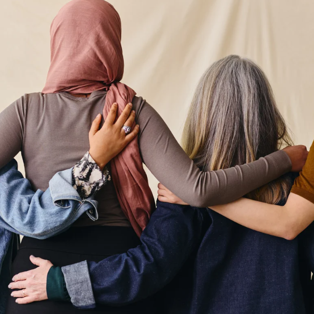 Four people side hugging facing away from the camera.