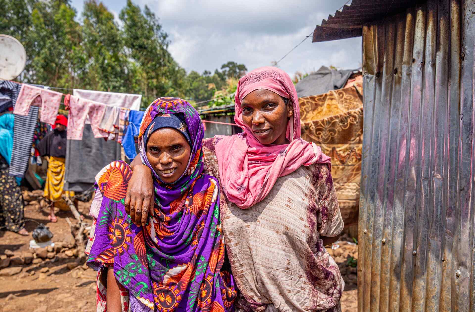 Two neighbors pose for a photo outside their home at the Keyra IDP site, Ethiopia.