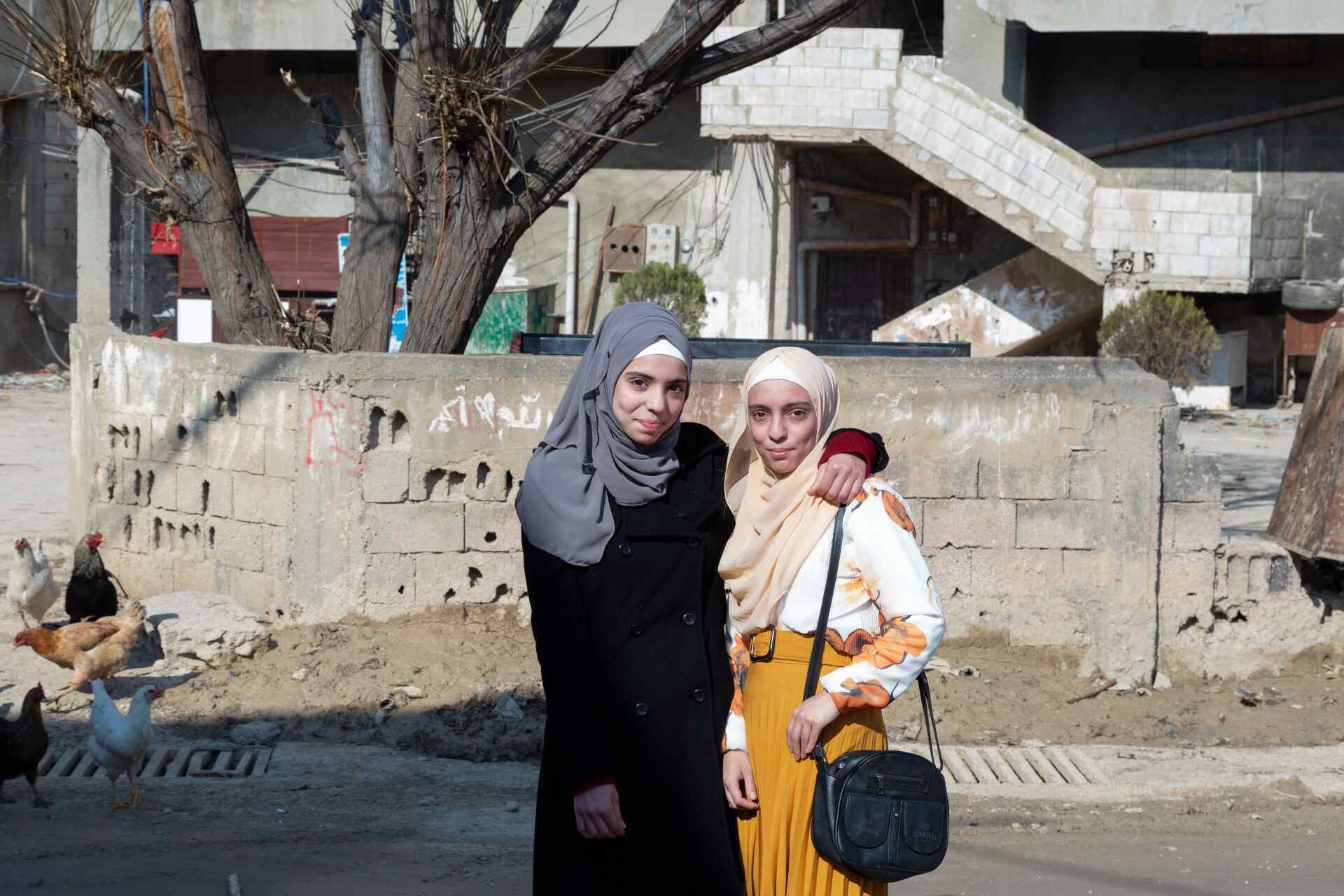 Two girls stand together and pose for a photo outside