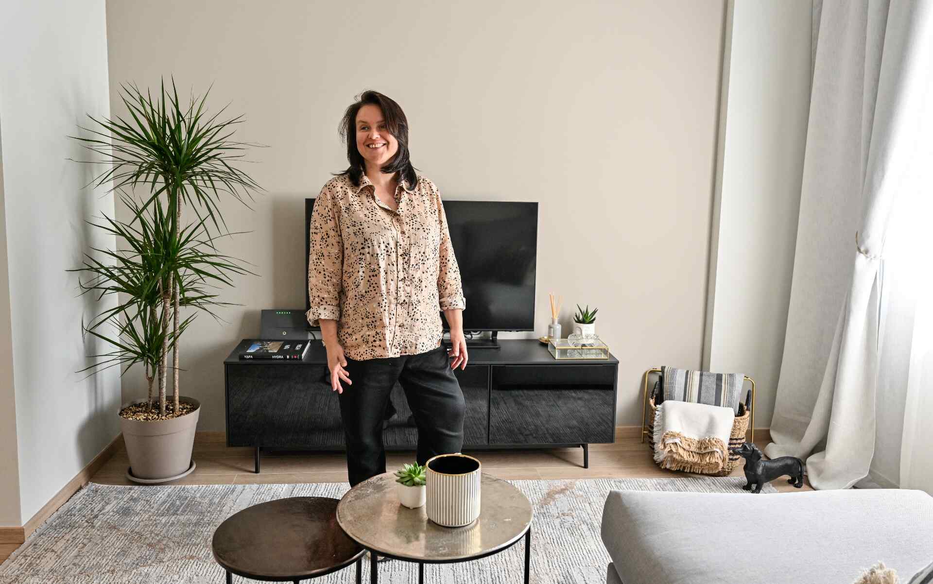 Alisa stands in the room of a home she has just decorated.