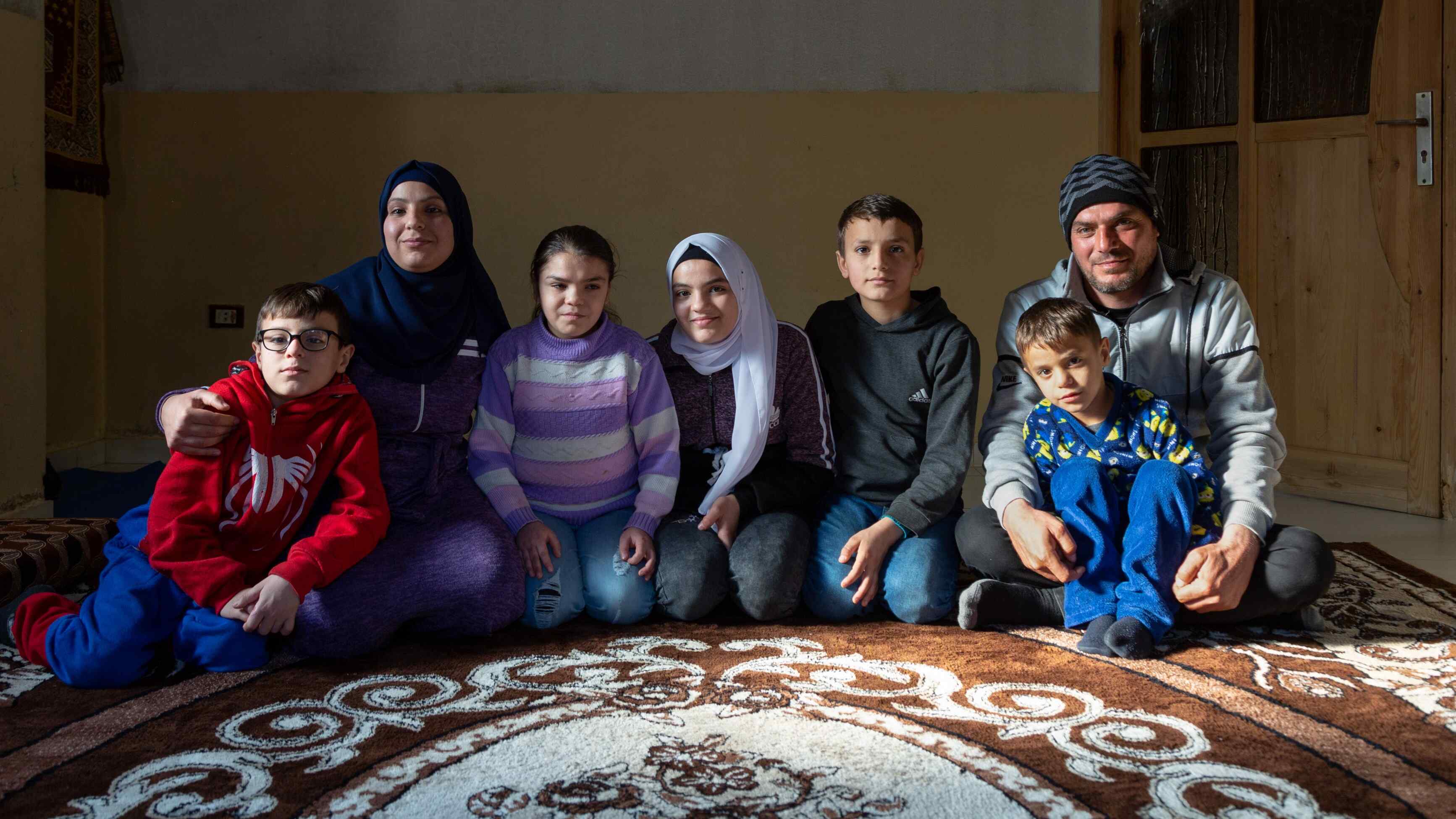 A family in Lebanon sit together in a living room and pose for a photo.