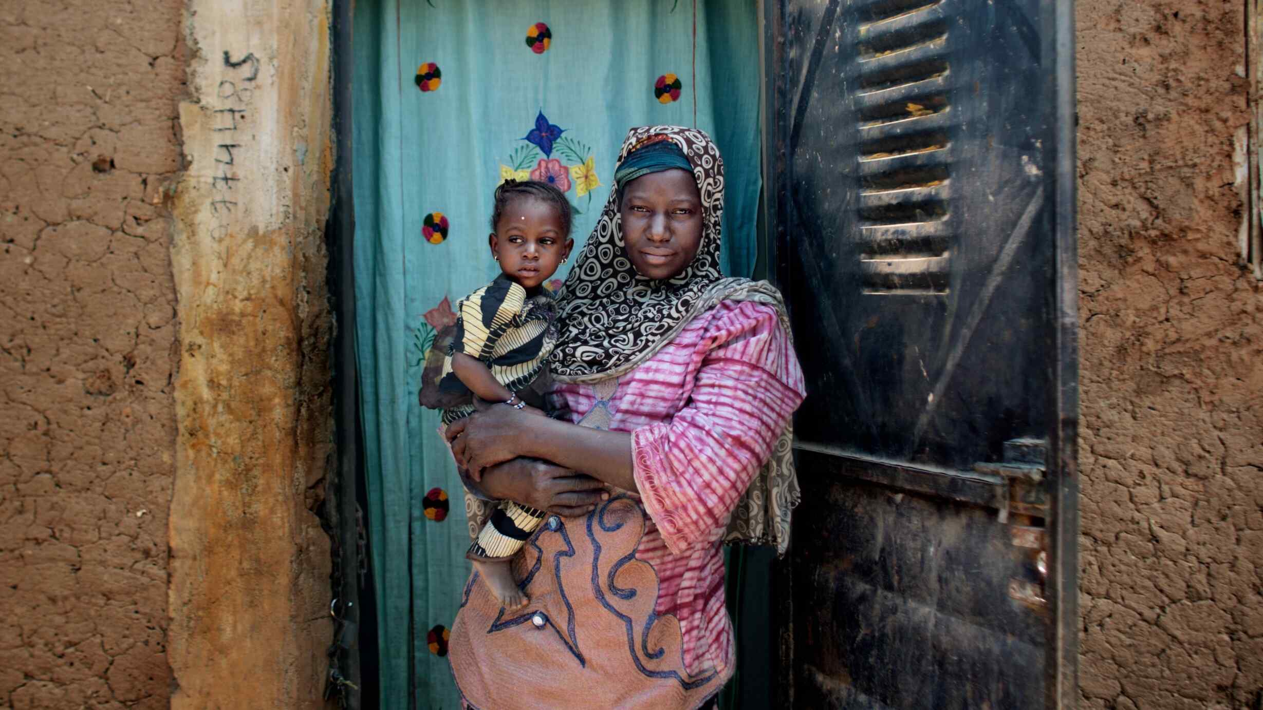 A woman holds her child while they pose for a photo.