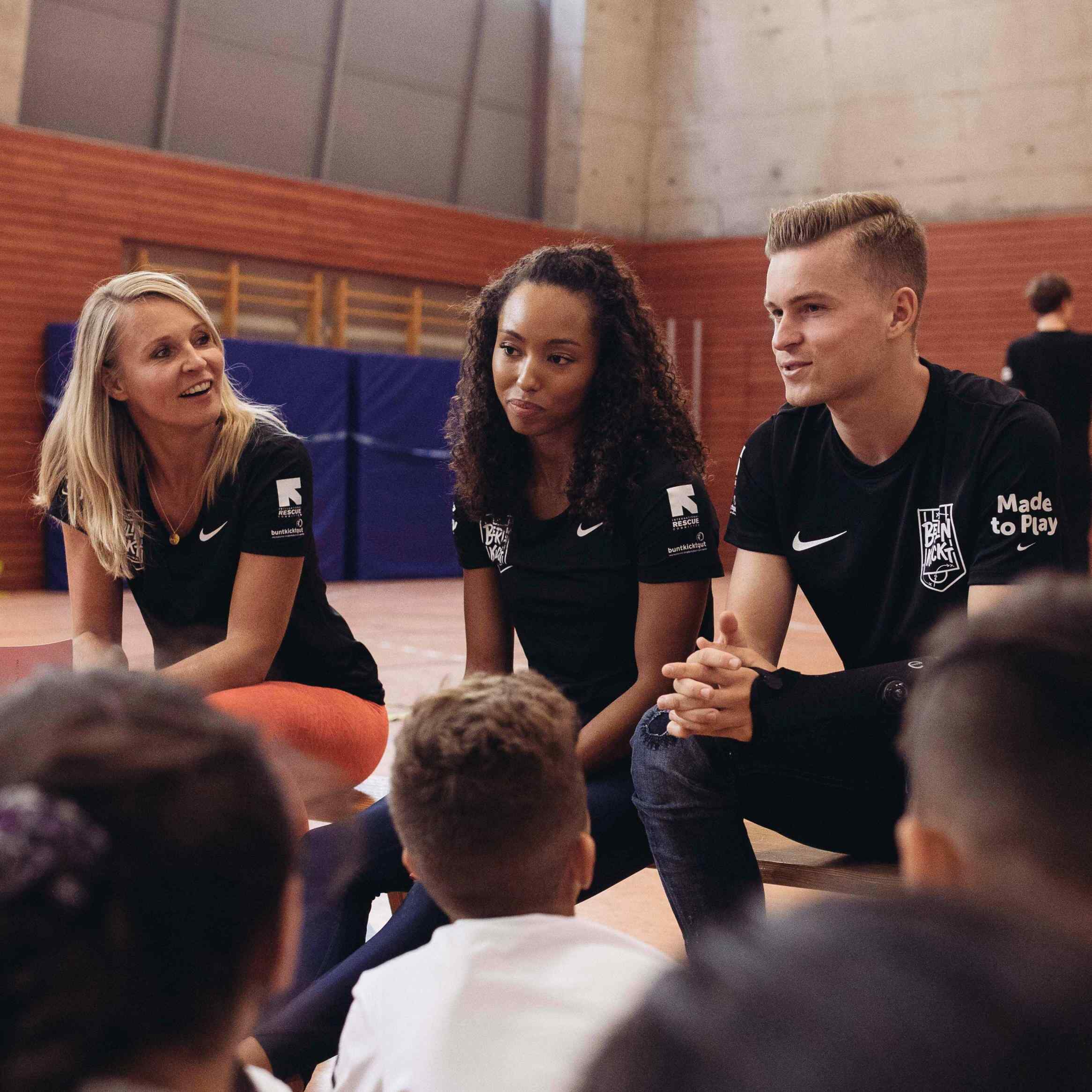 Schüler*innen, die am Berlin Kickt Programm von International Rescue Committee teilnehmen bei einer Trainingseinheit mit den Spitzensportlern Jacqueline Otchere (o.M.) und Maximilian Mittelstädt