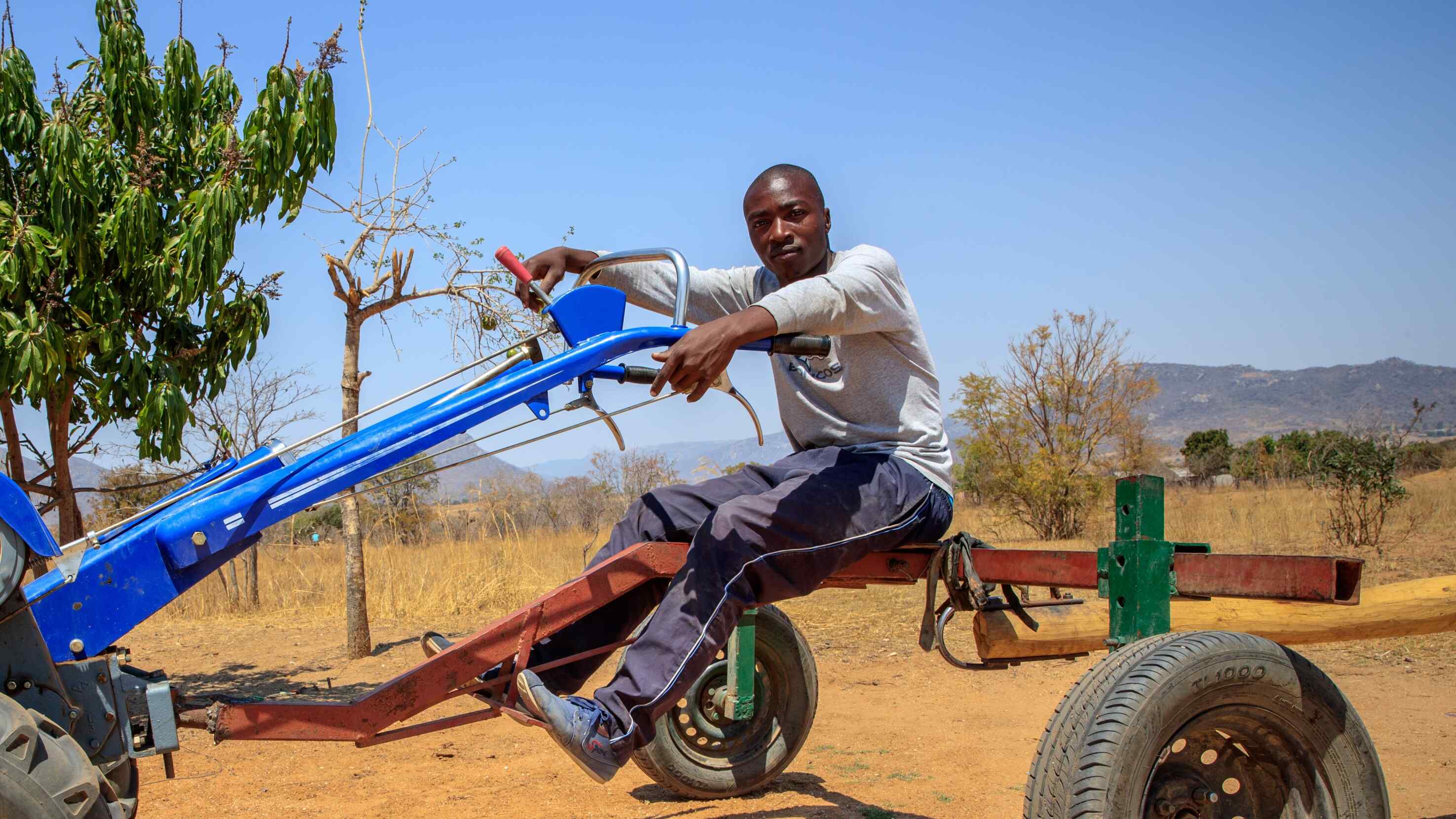 A man in Zimbabwe sits atop a piece of farming machinery.