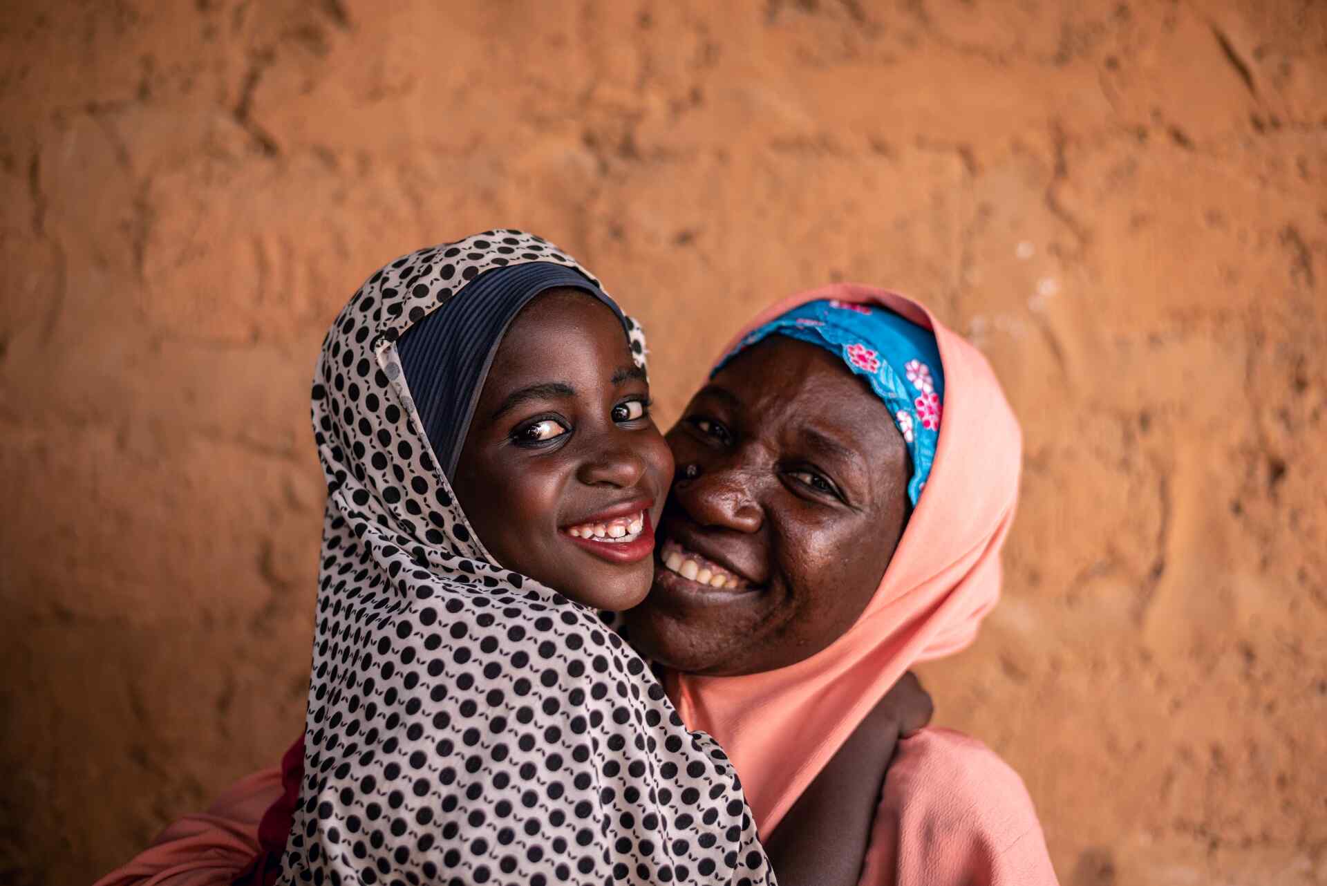 A mother and a daughter embrace and share a smile while posing for a photo.
