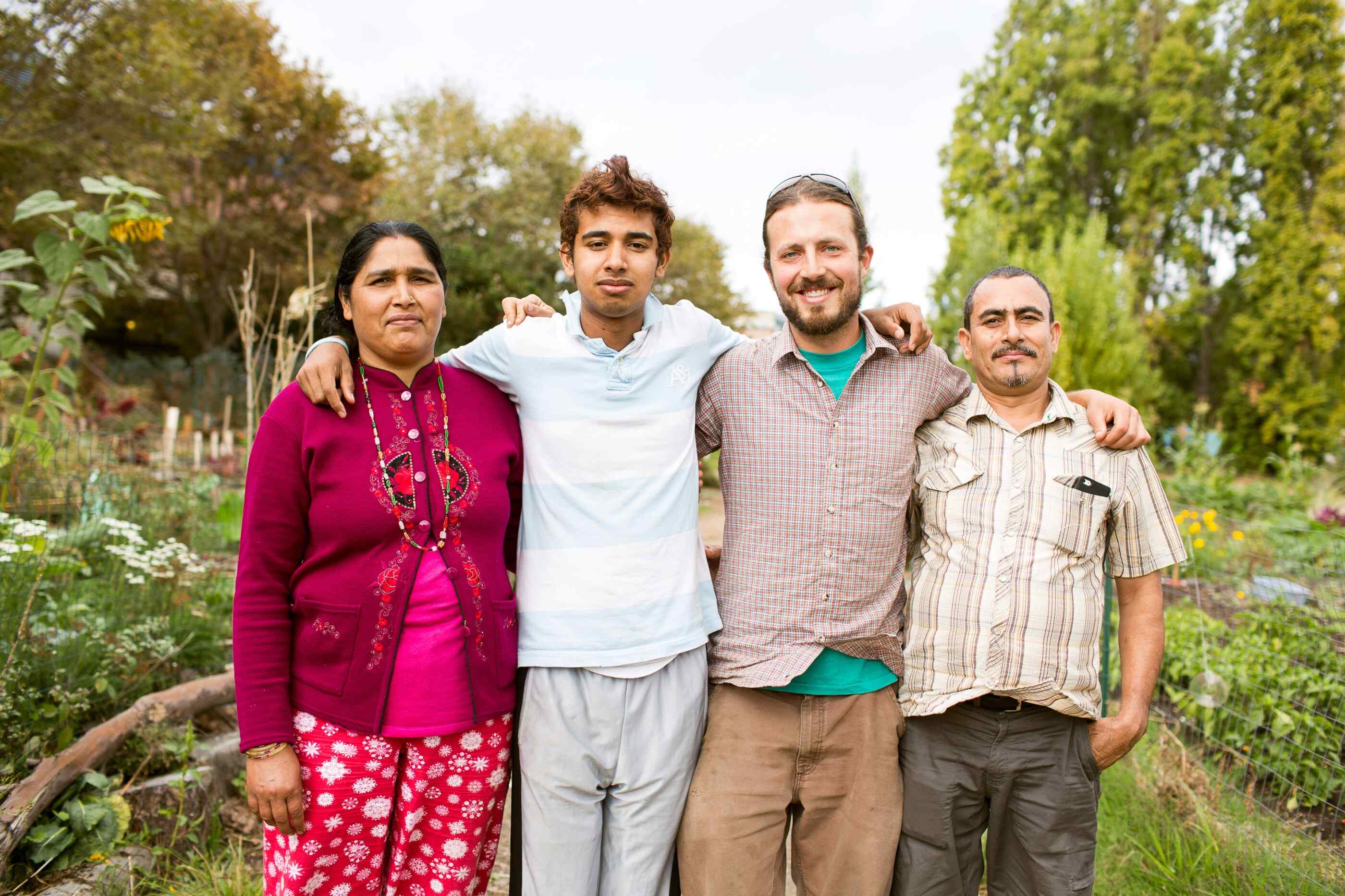 Four people pose for a picture outdoors in a garden.