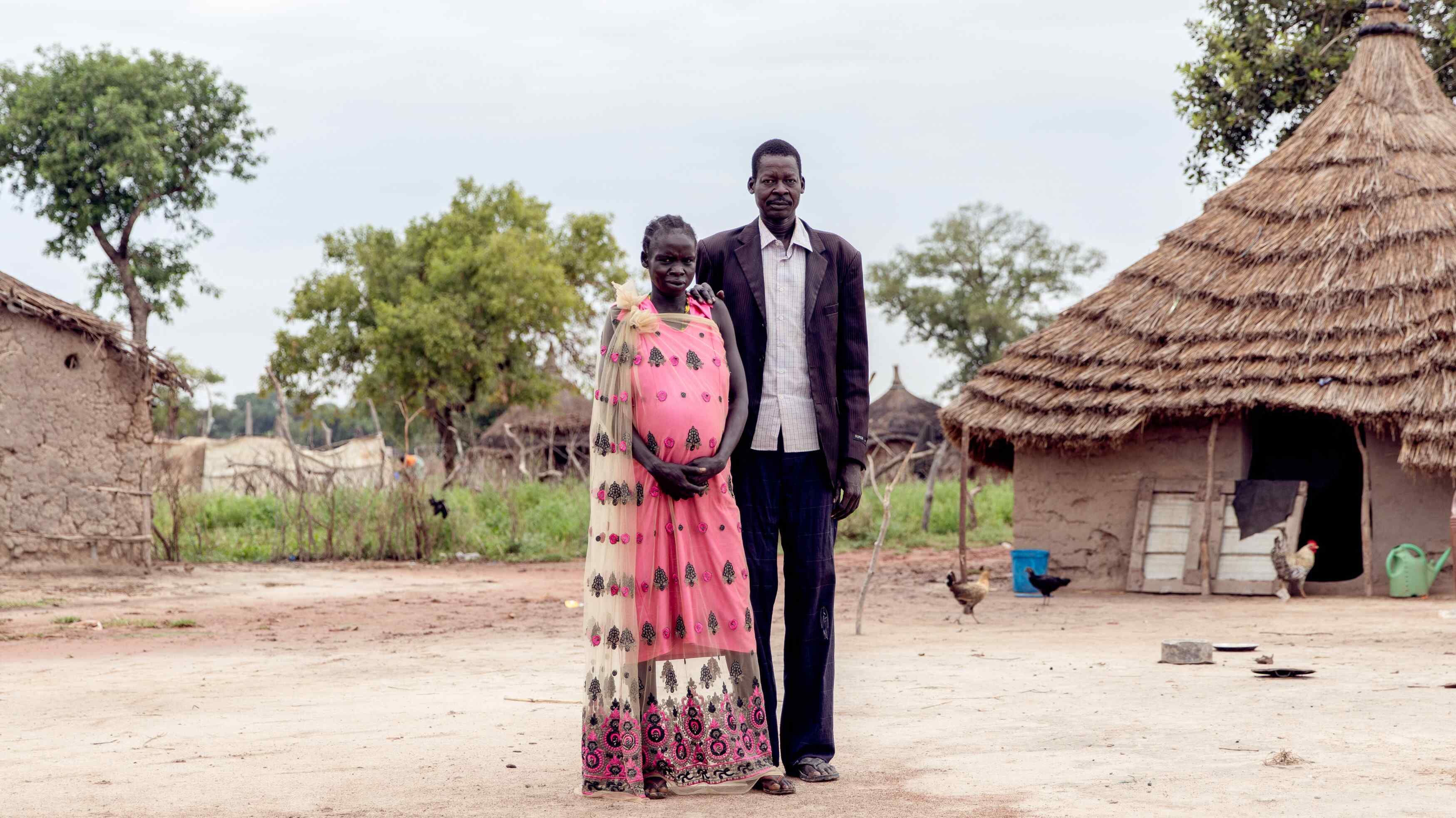 A man and woman poses for a photo outside their home in South Sudan.