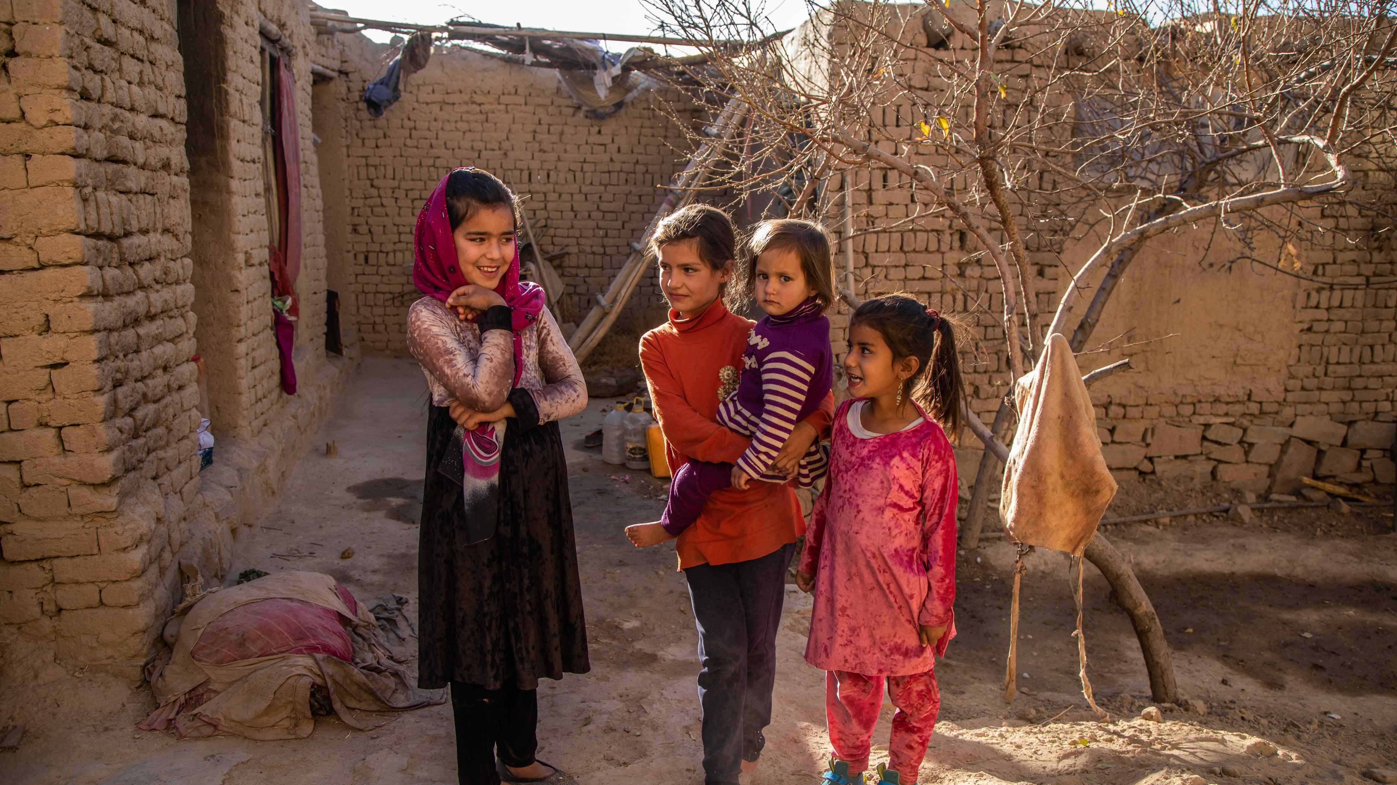 Four girls pose for a photo in an outdoors courtyard.
