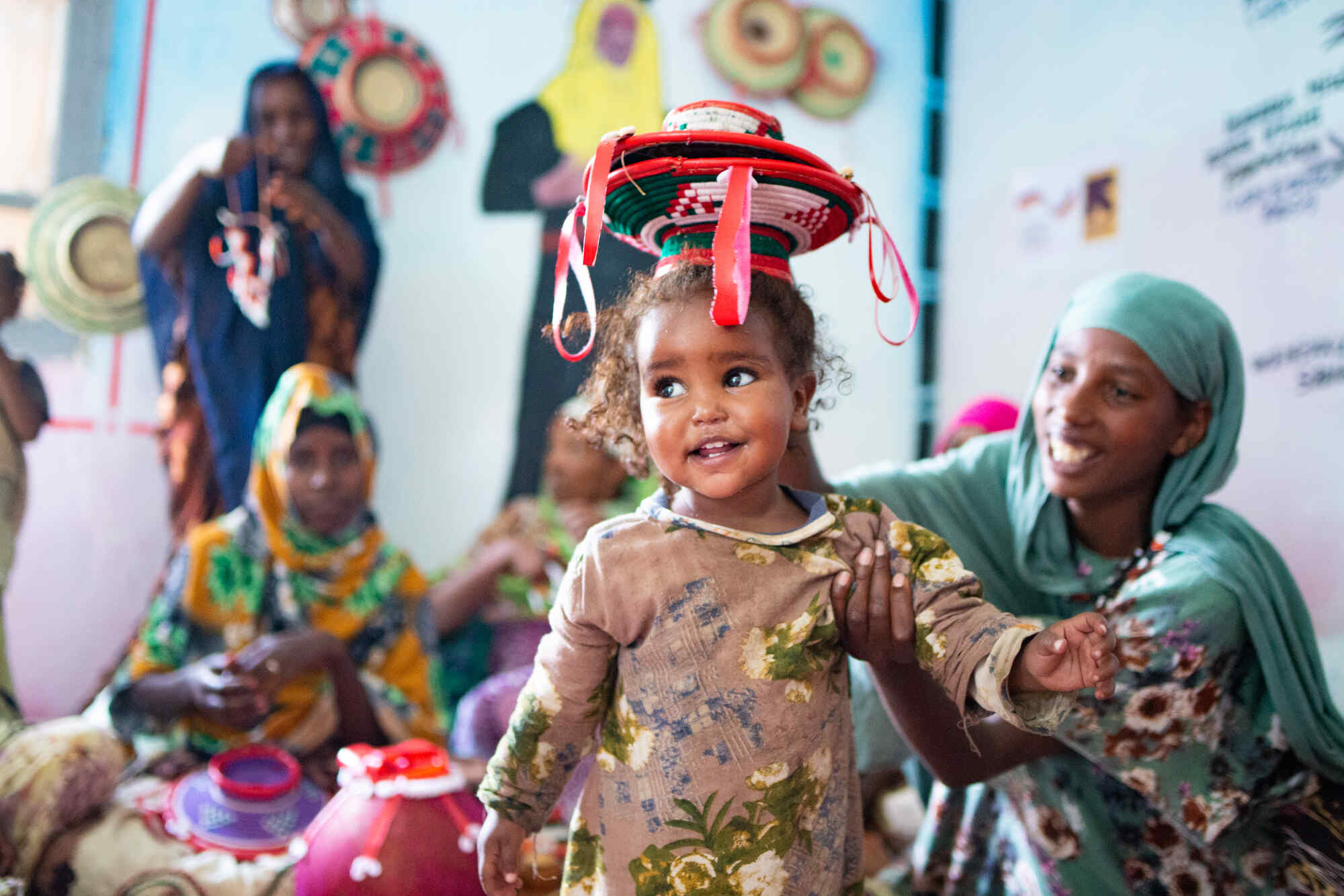 Ein kleines Mädchchen lacht während sie typisch äthiopische Handwerkskunst präsentiert