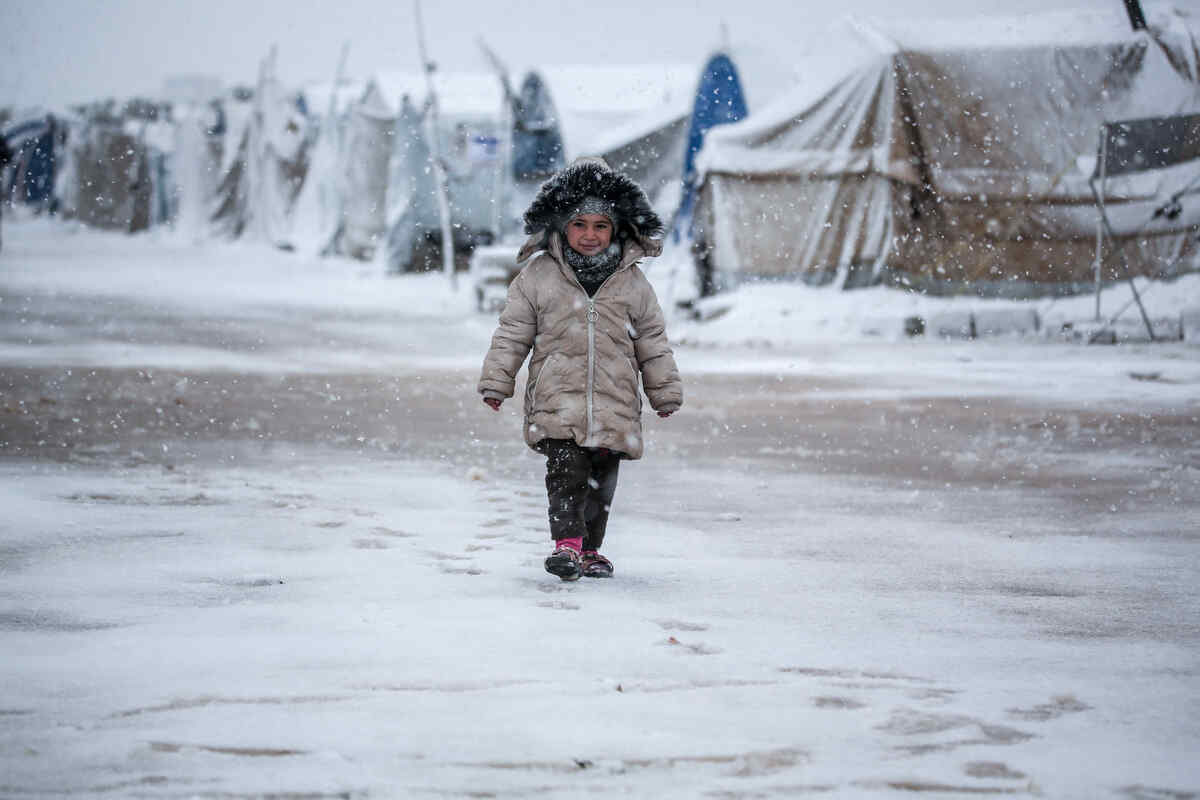 Liten flicka går mitt i ett vinterlandskap i Syrien. 
