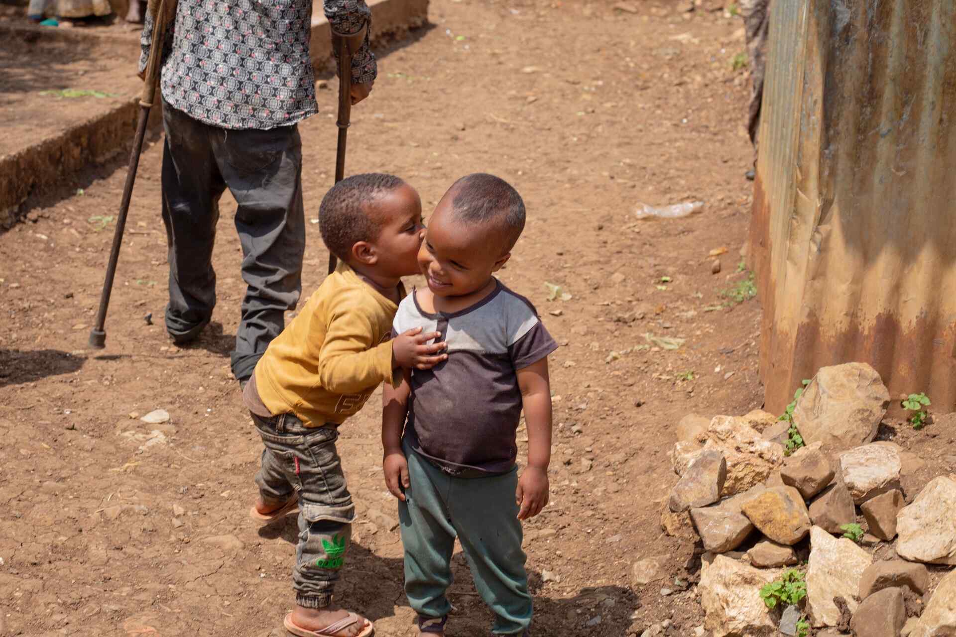 Two young children in Ethiopia embrace outside. They smile together.