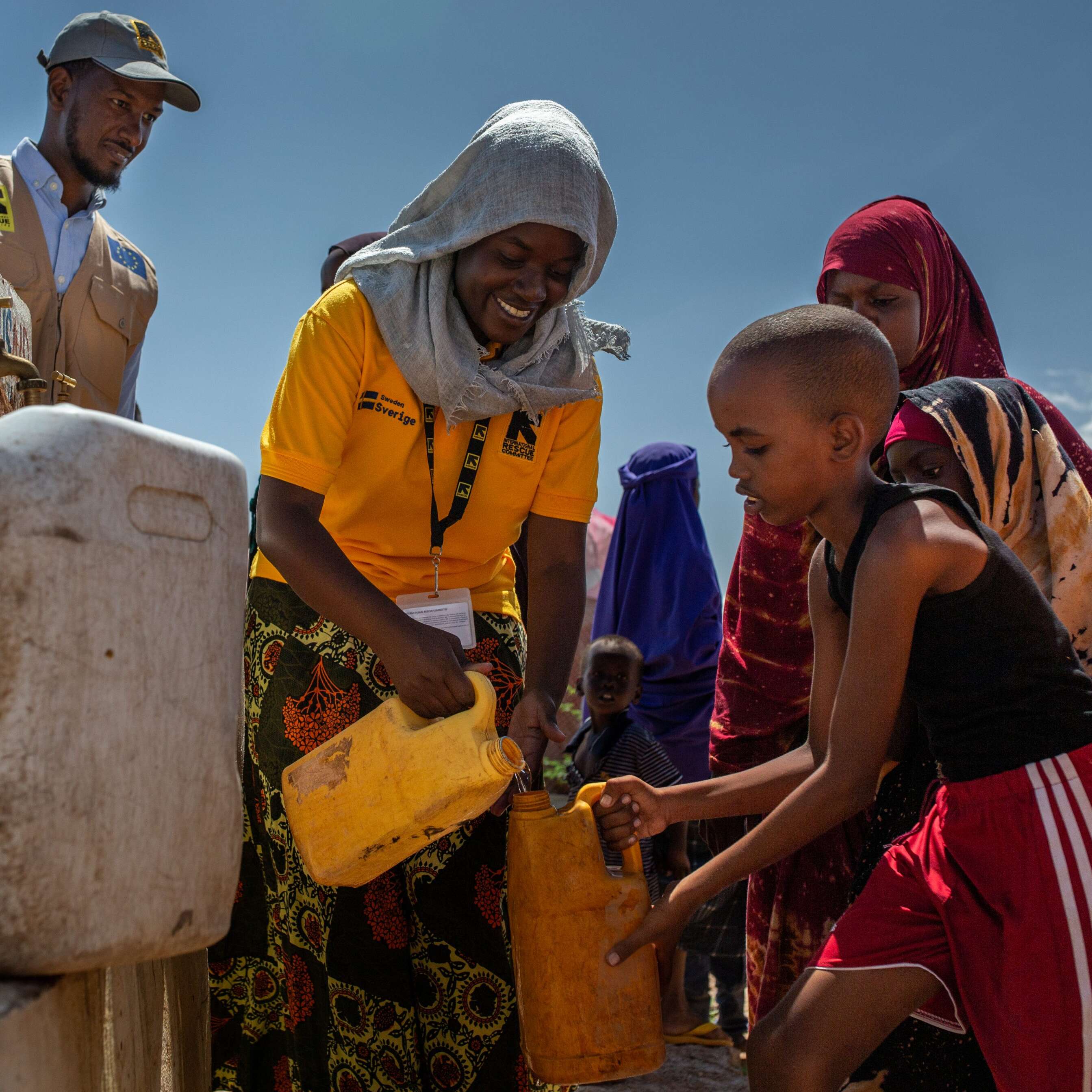 Volunteers aiding children gathering water.