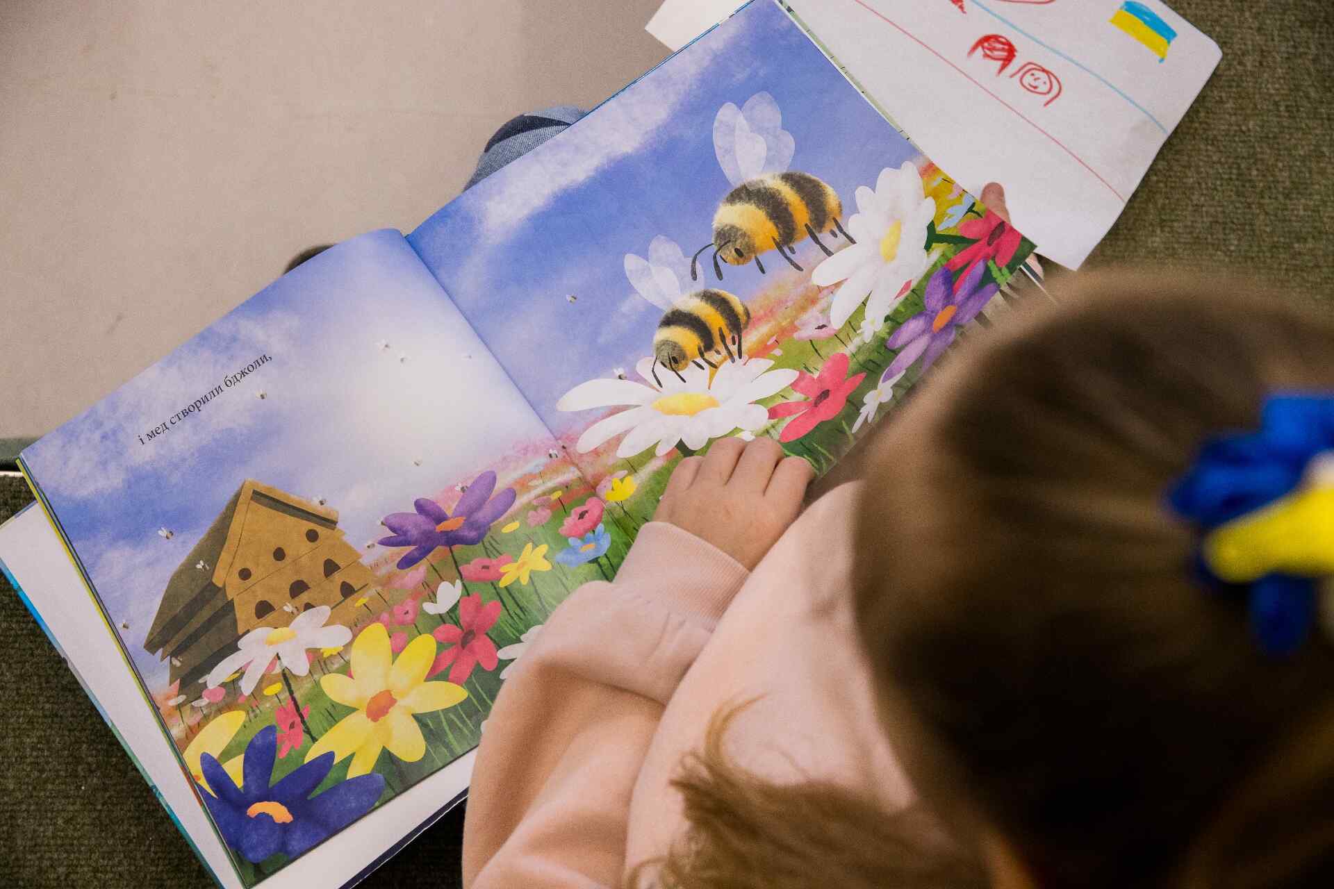 A Ukrainian child reads a book translated to their native language.
