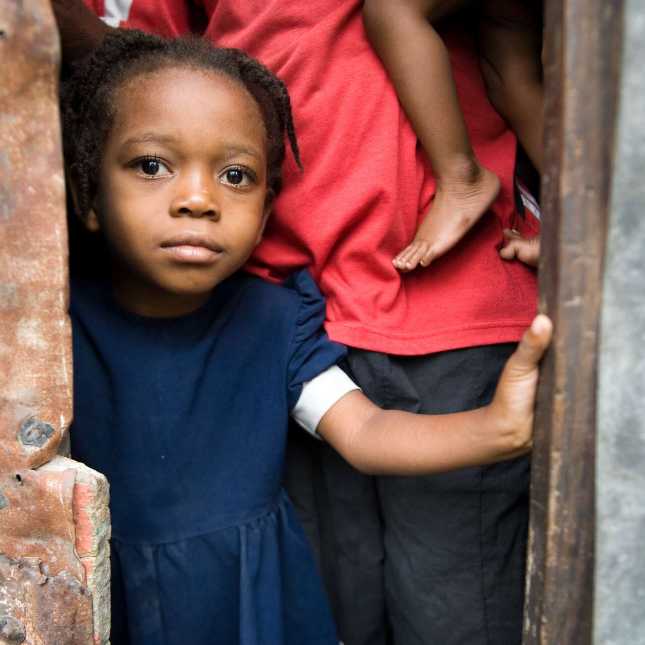 A young girl stands in a doorway in Haiti, looking at the camera