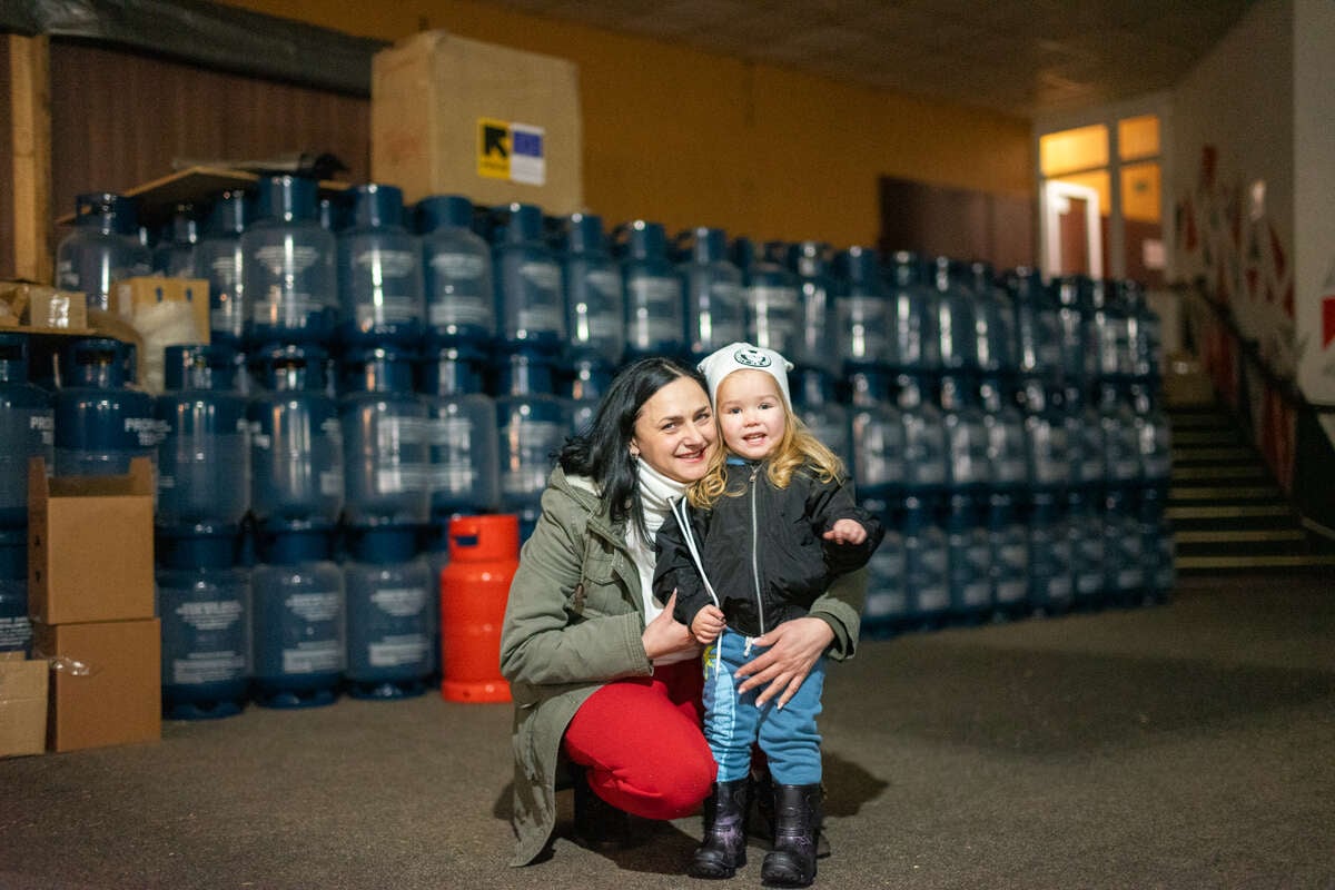 A mother and her small child in front of emergency supplies provided by the IRC and EU