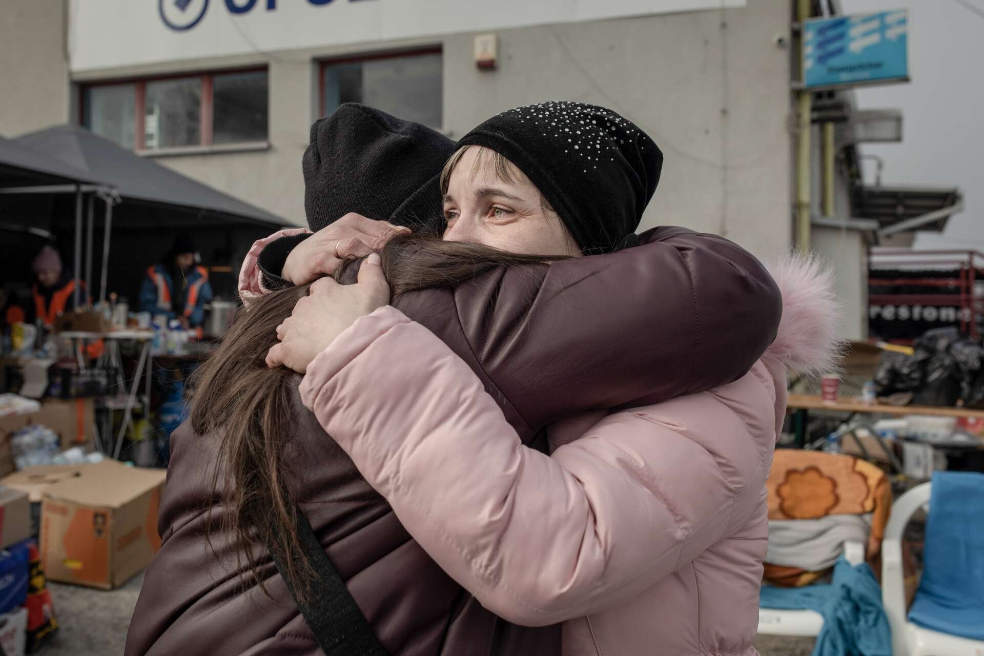 A mother and her adult daughter embrace in a tight hug at a border crossing near the Ukrainian - Polish border.