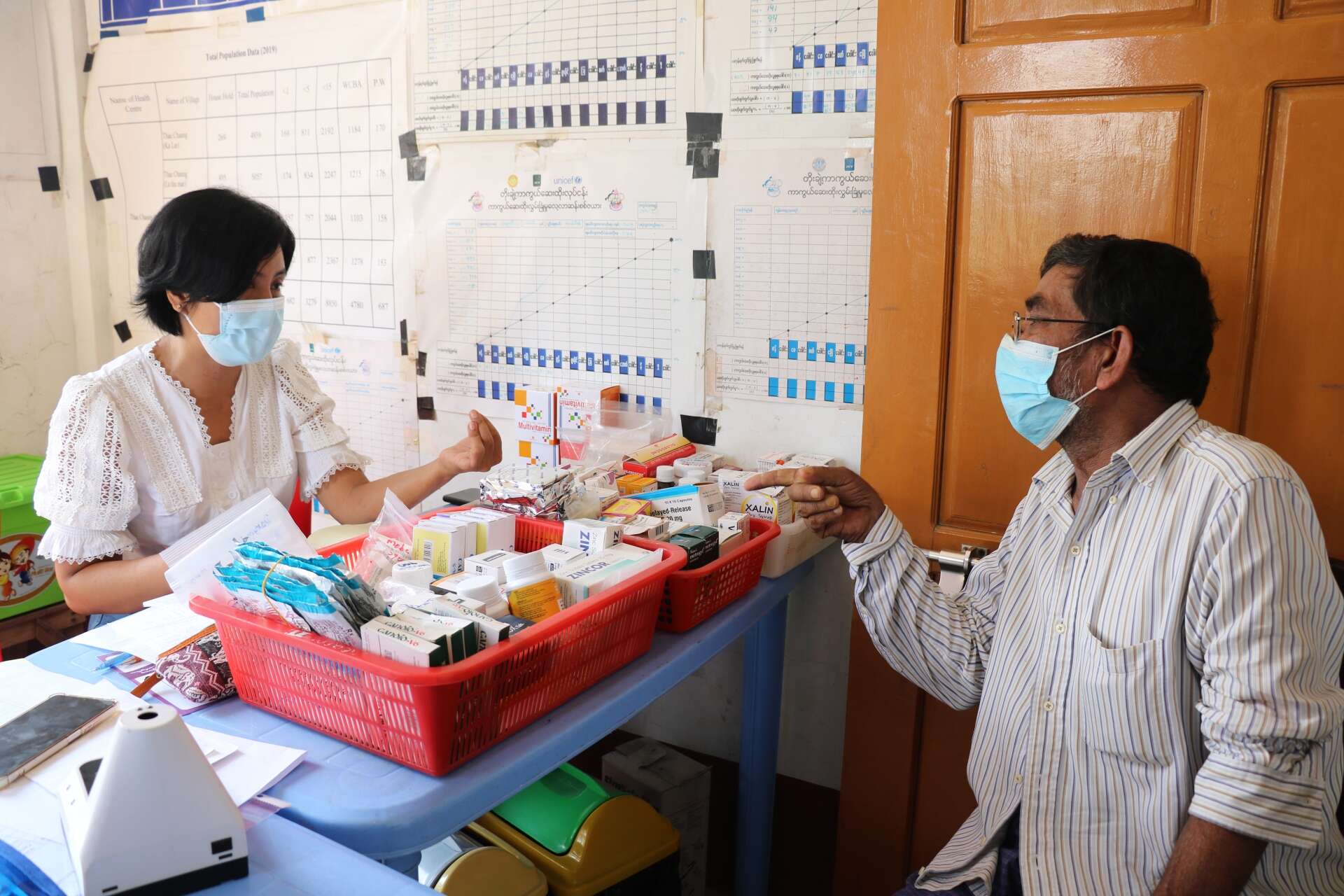 An IRC clinic nurse sits across from a patient who she gives medical advice to.
