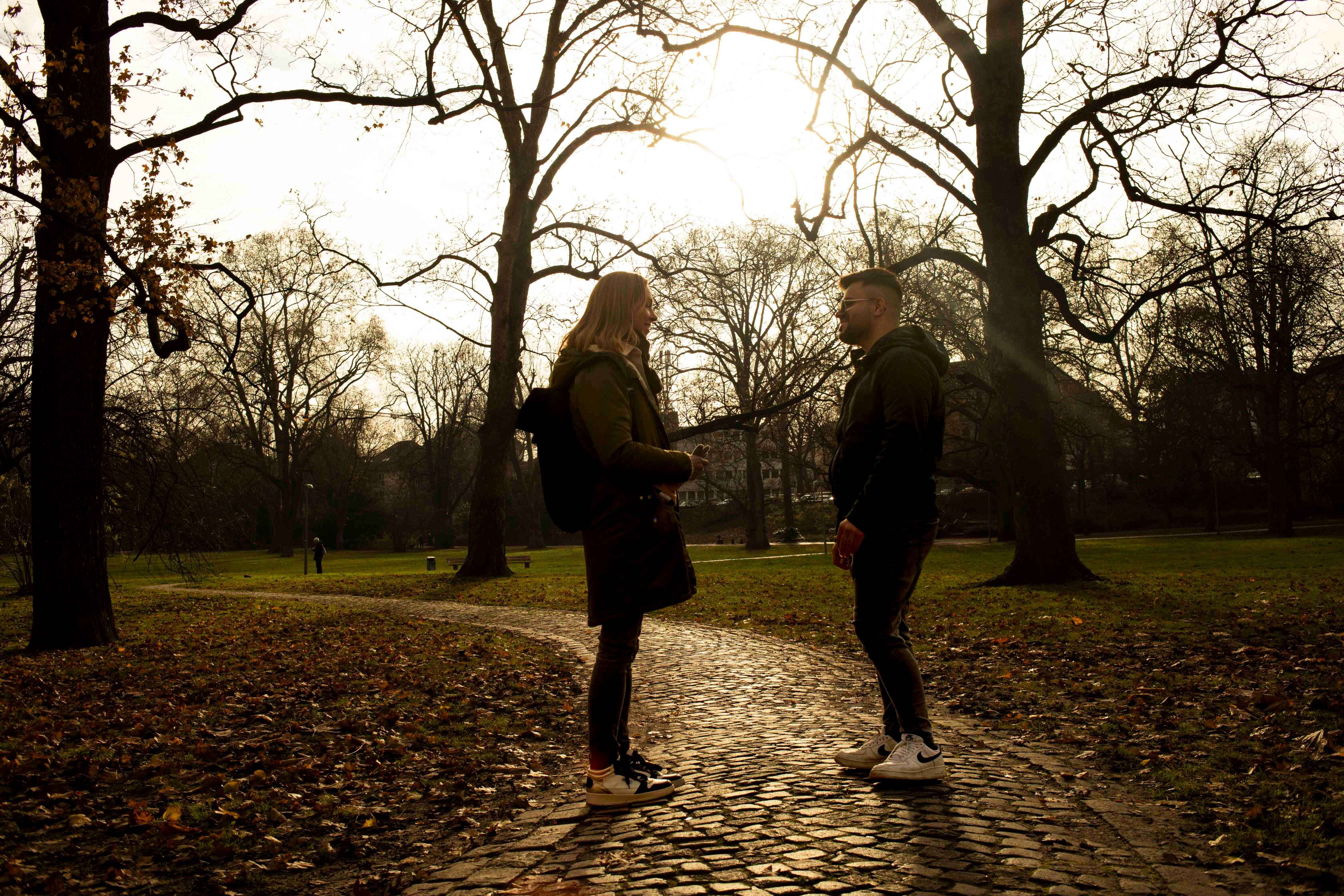 Ein junger Mann und eine Frau stehen draußen in einem Park.