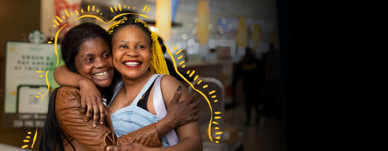Two women embrace, smiling.