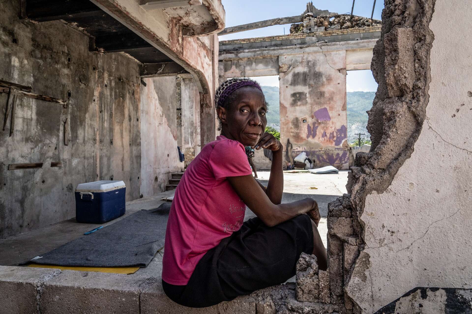 A woman poses for a photo in the ruins of a structure in Haiti.
