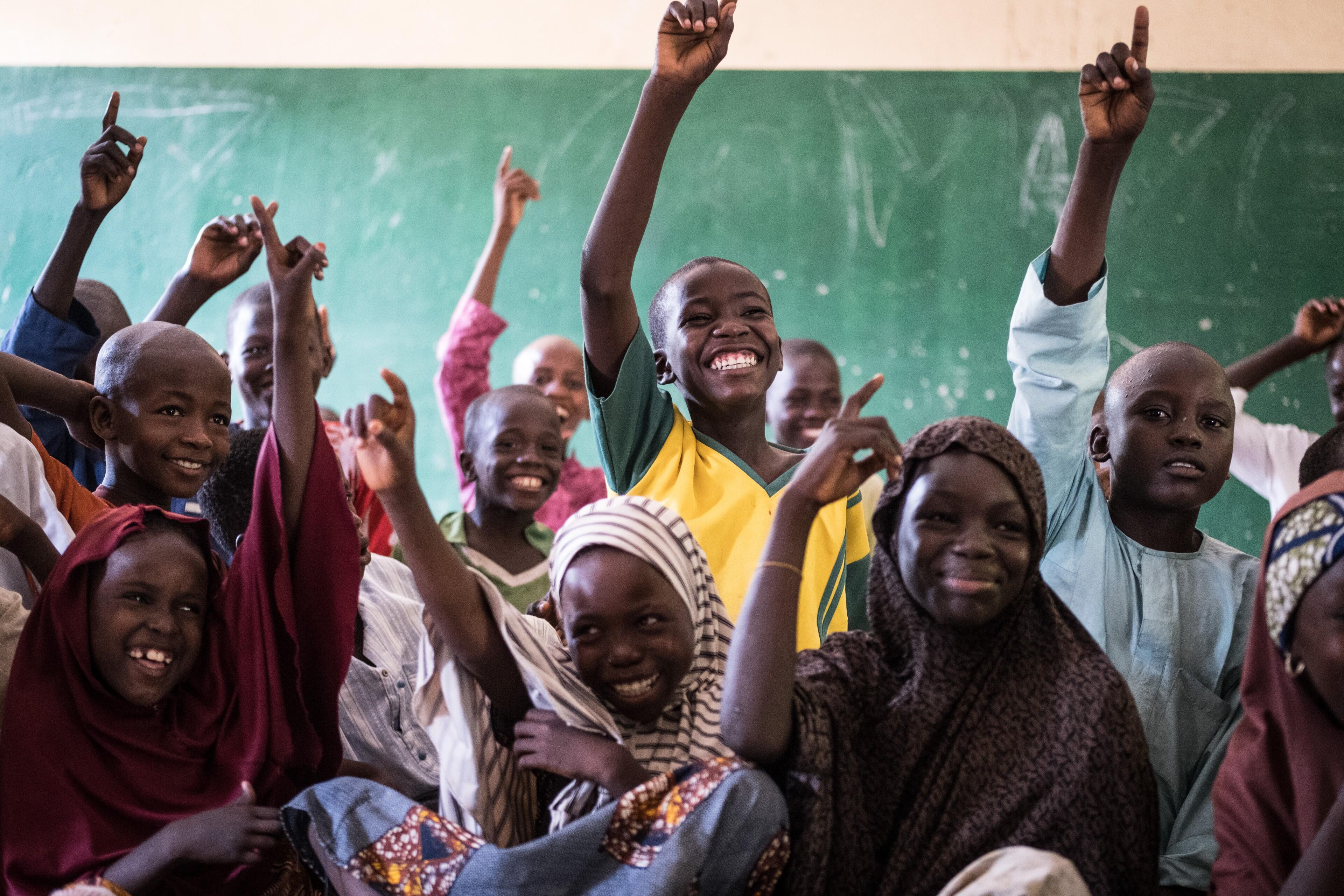 Students excitedly raise their hands in class at an International Rescue Committee supported school in Nigeria.