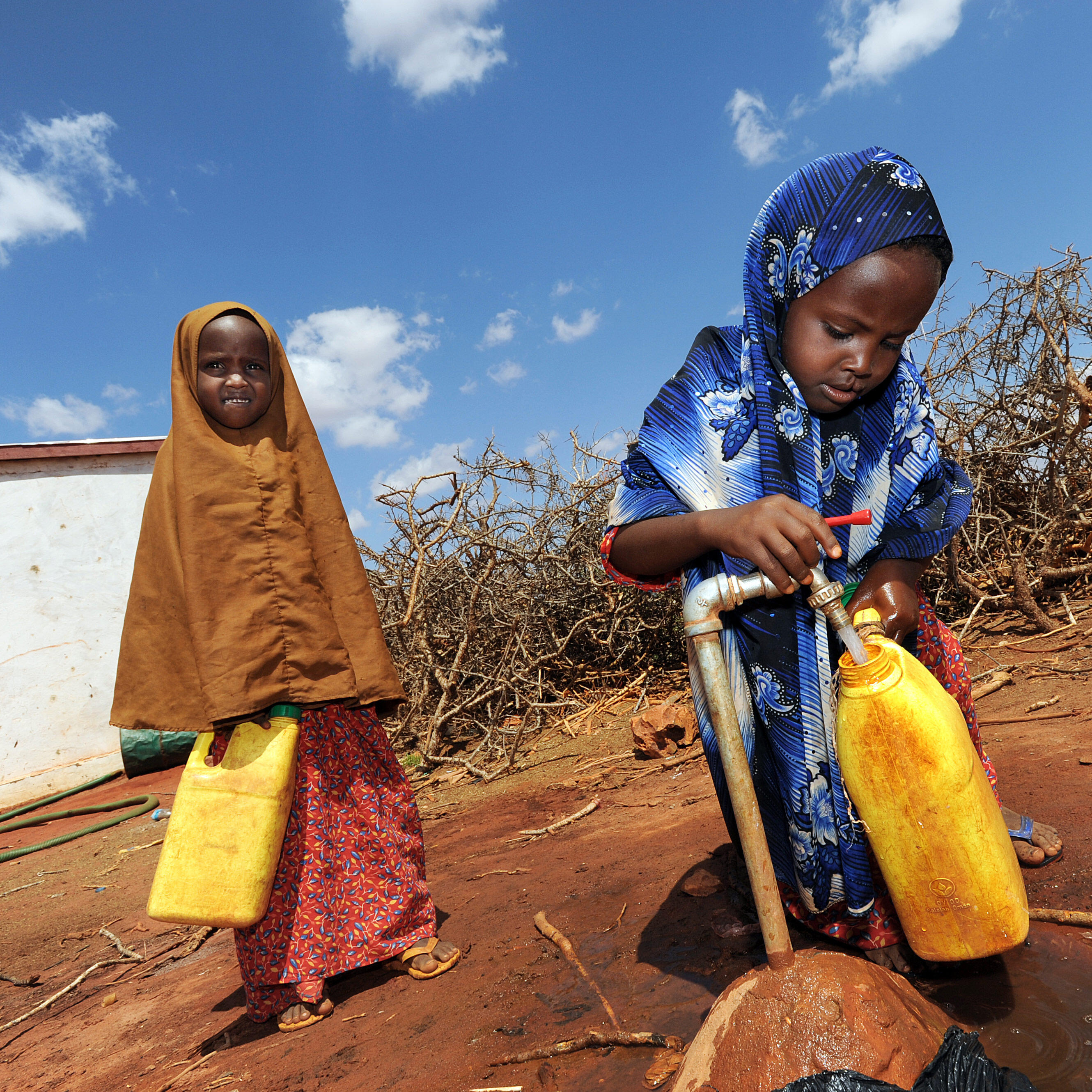 Two girls fill water jugs at an IRC-installed tap in Galkayo, Somalia 