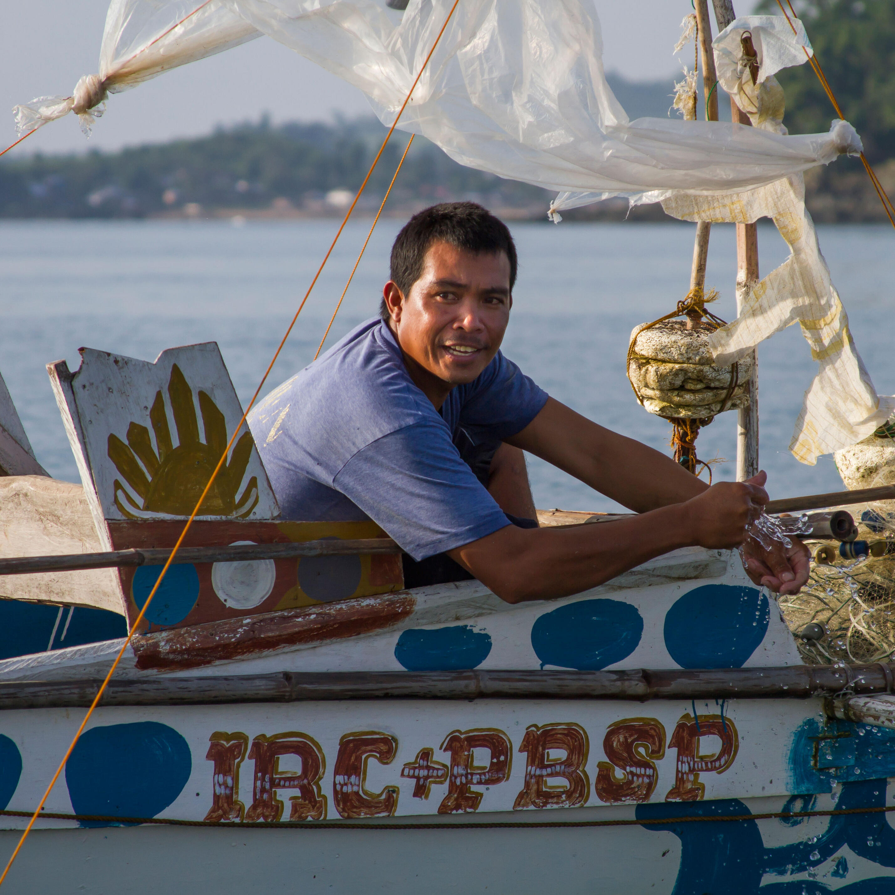 A Filipino fisherman sits in his boat on the water.