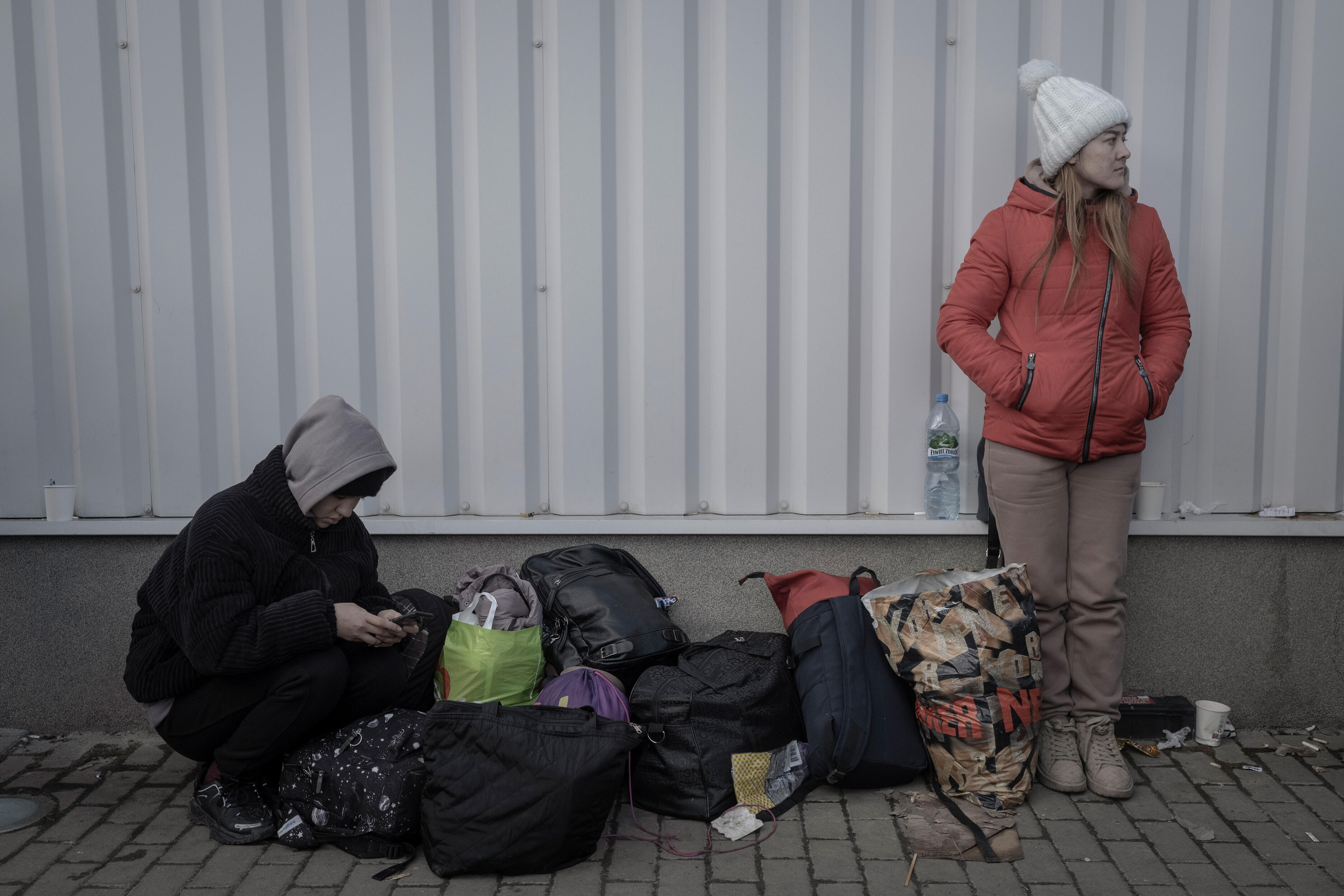 two Ukrainian refugees stand with their bags