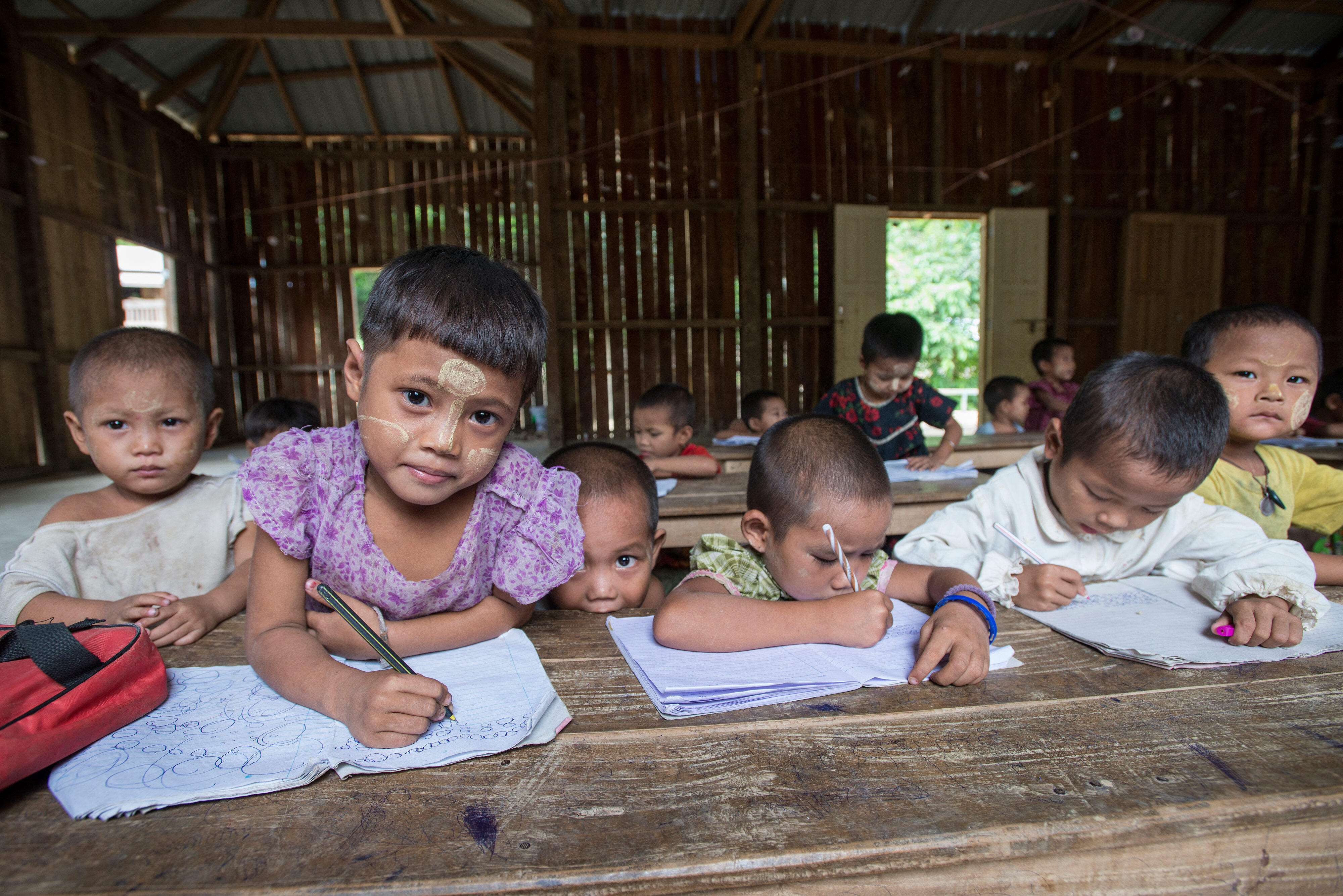 Refugee children hold pencils in a classroom at a refugee camp in northern Thailand