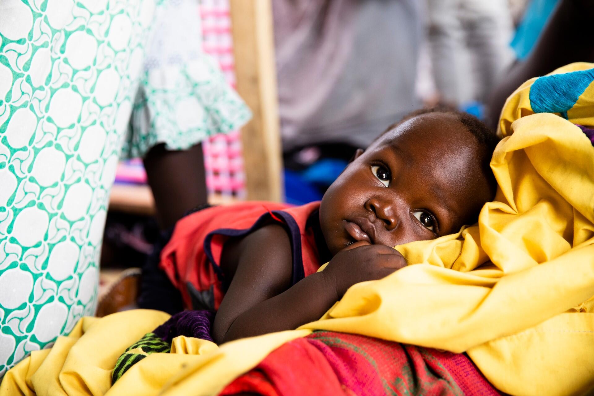 A baby is held by a woman at a health facility in South Sudan