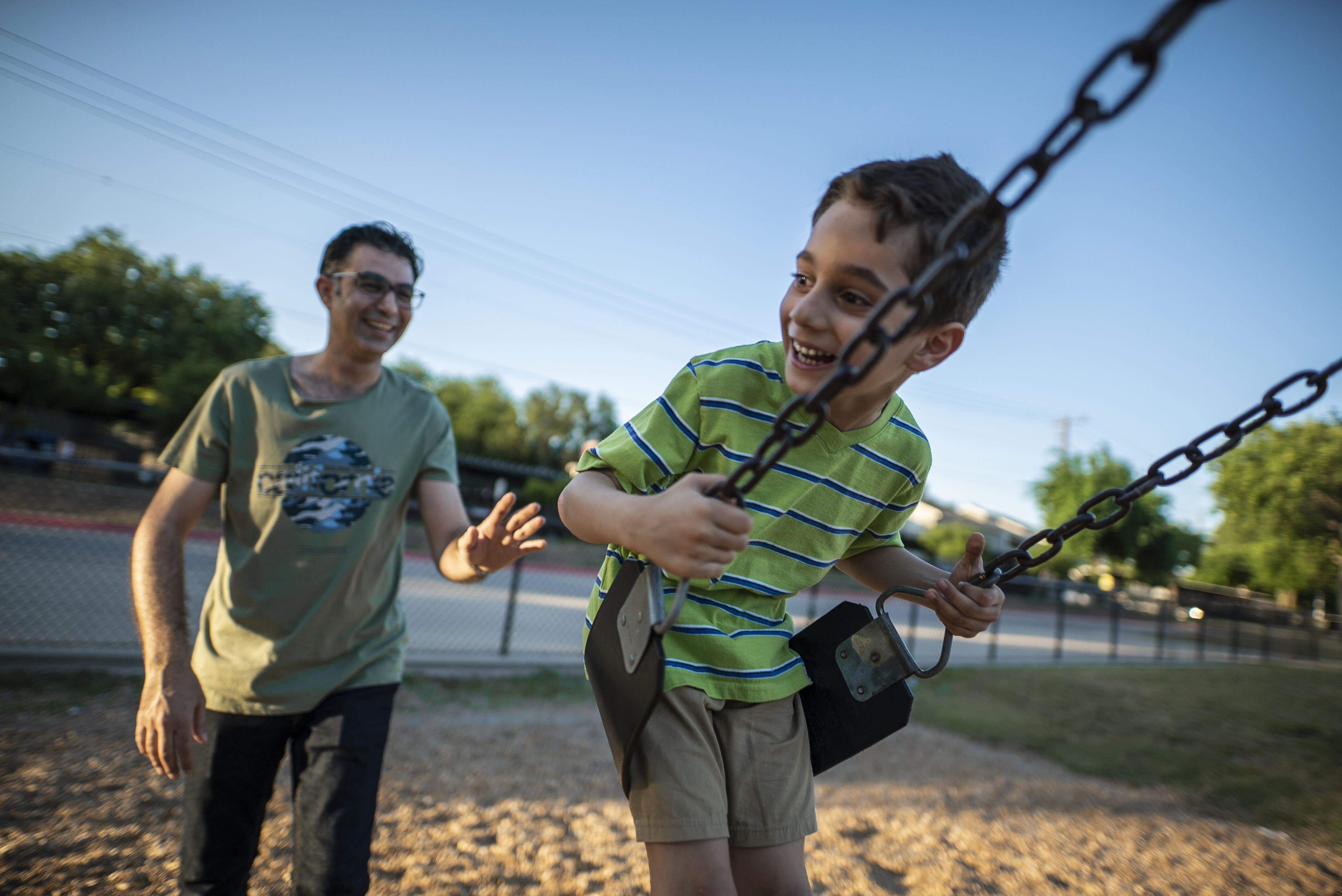A father, Junaid, pushes his son Ridha on a swing in a playground in Dallas. The family arrived in the U.S. as refugees.